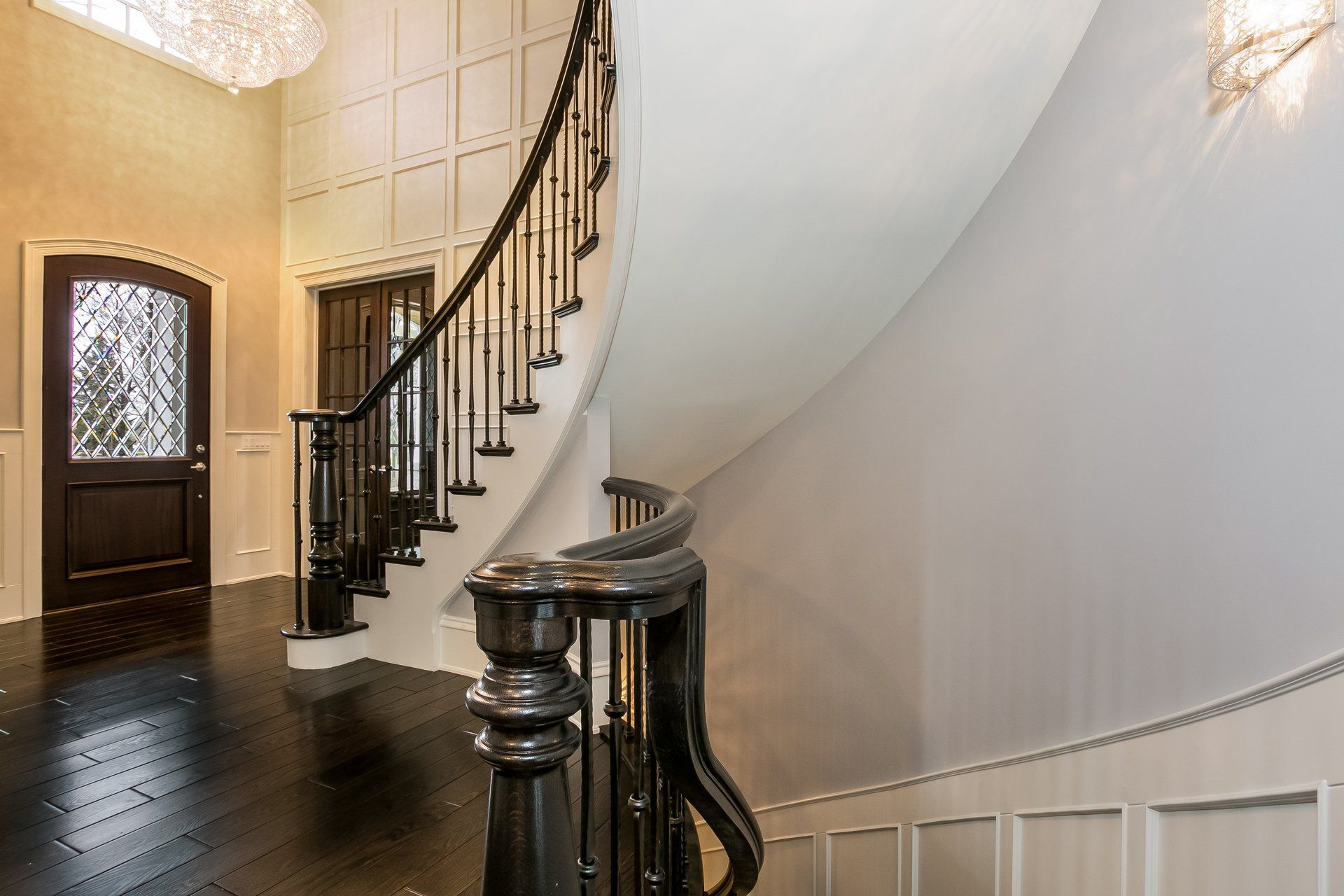 A curved staircase in a house with a chandelier hanging from the ceiling