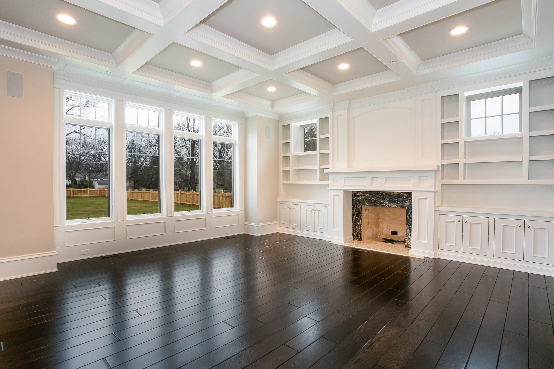 An empty living room with hardwood floors and a fireplace.