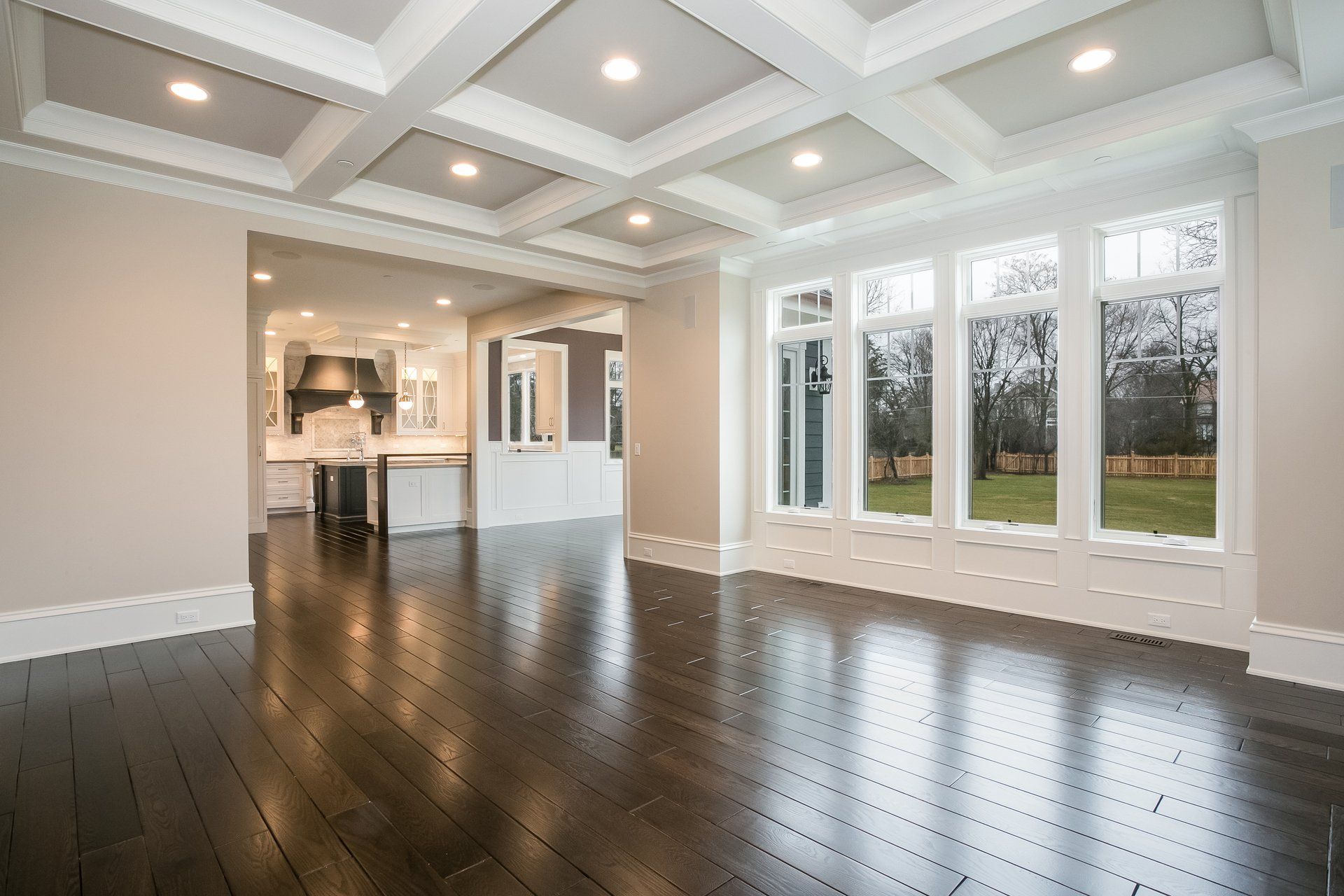 An empty living room with hardwood floors and lots of windows.