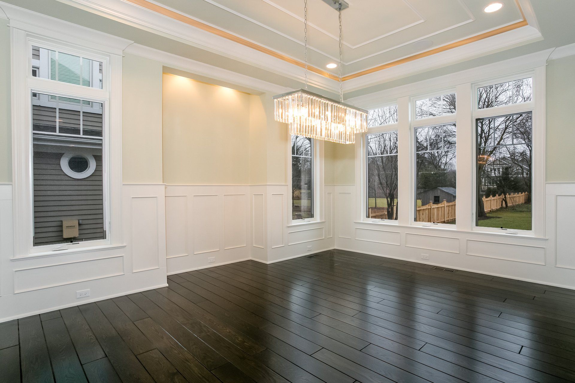 An empty dining room with hardwood floors and a chandelier.