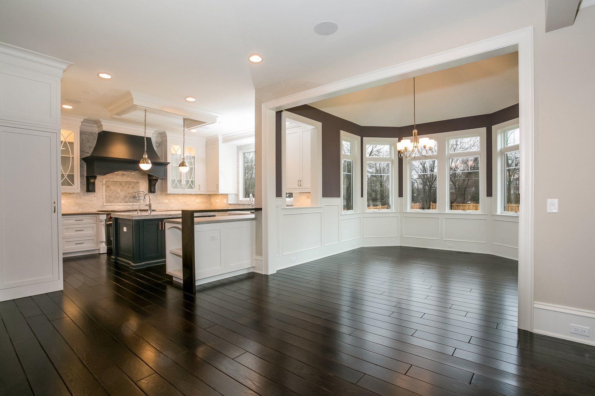 A large empty room with hardwood floors and a kitchen.