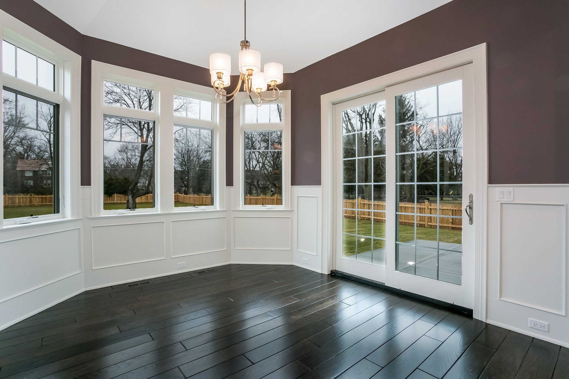An empty room with sliding glass doors and a chandelier