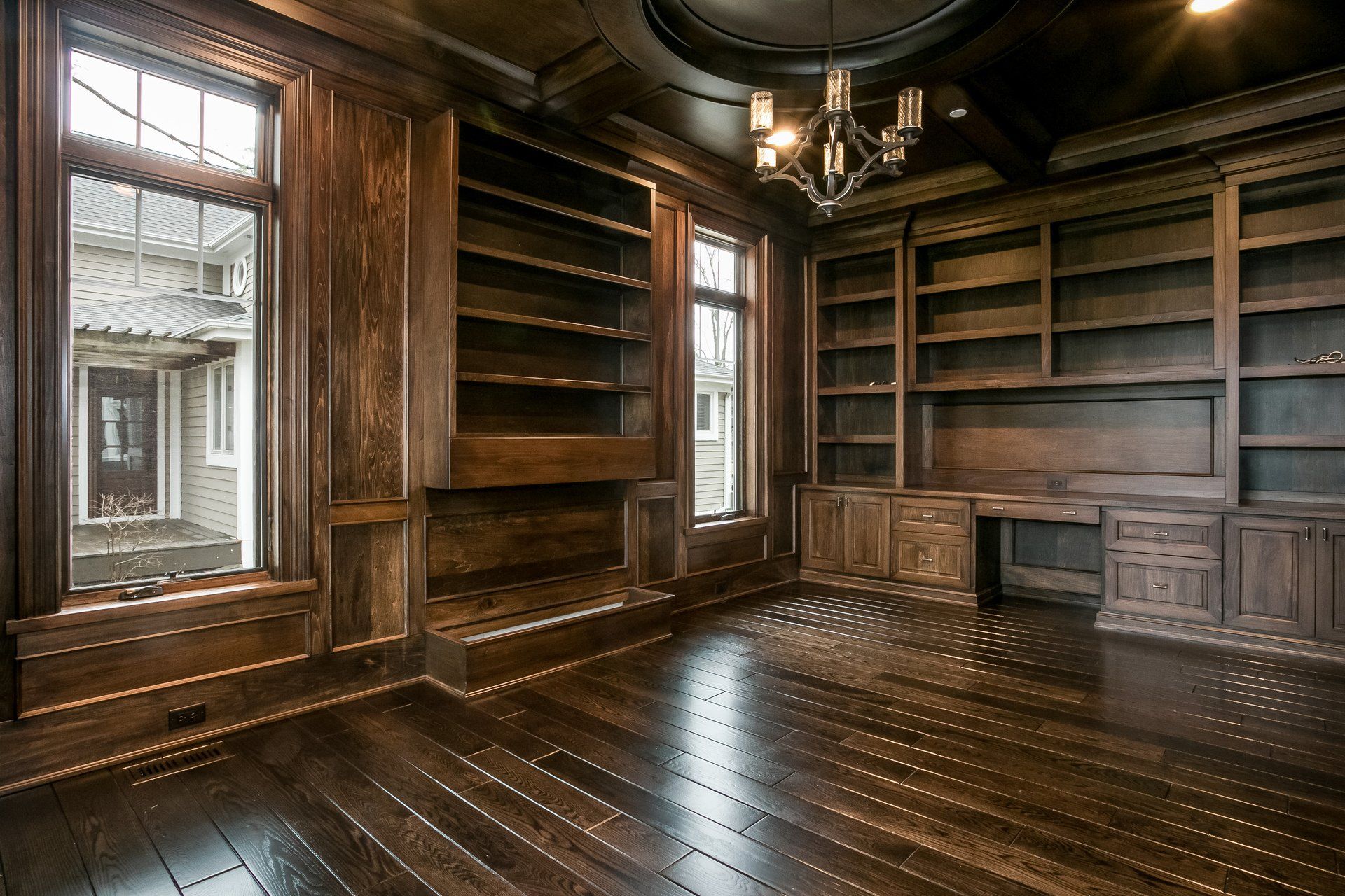 A large empty room with wooden shelves and a chandelier.