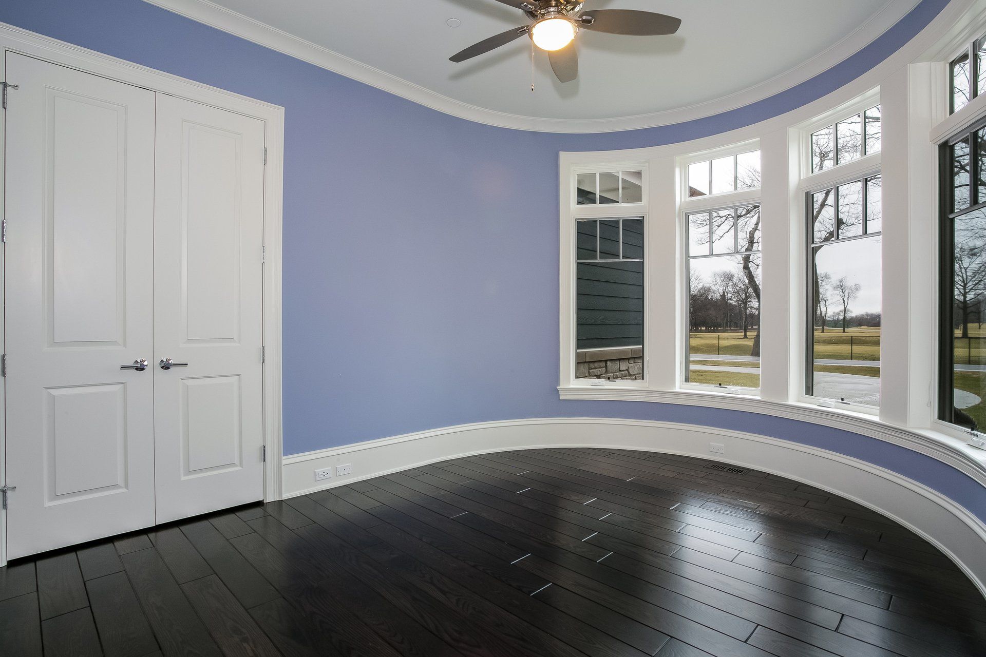 An empty room with blue walls and a ceiling fan
