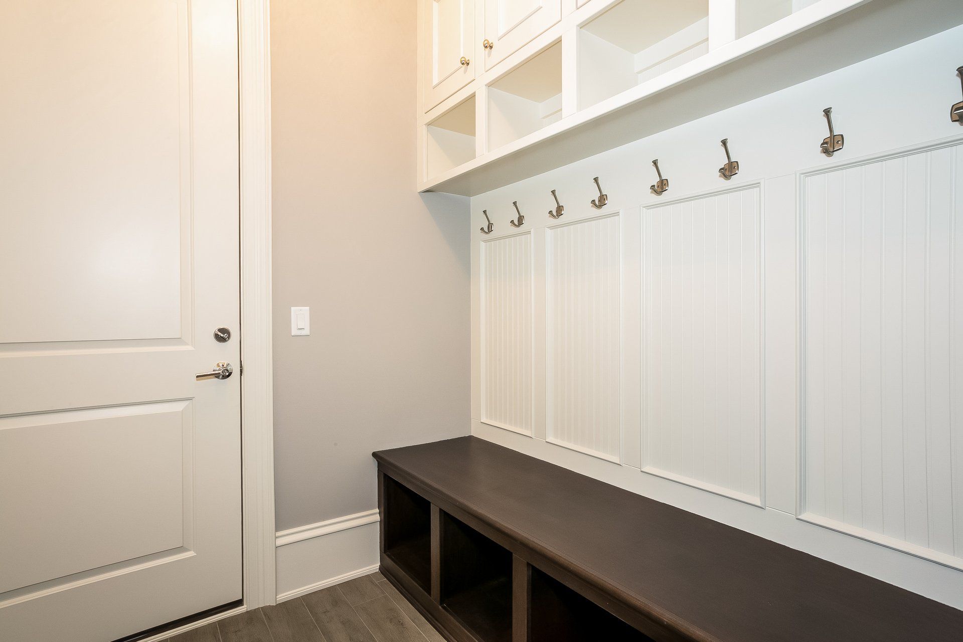 A mud room with a bench and hooks on the wall.