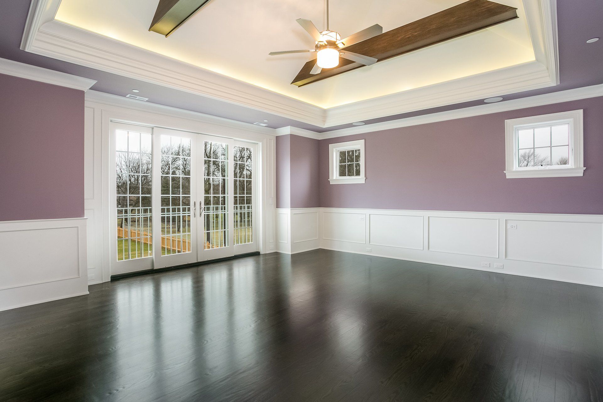 An empty room with purple walls and a ceiling fan.