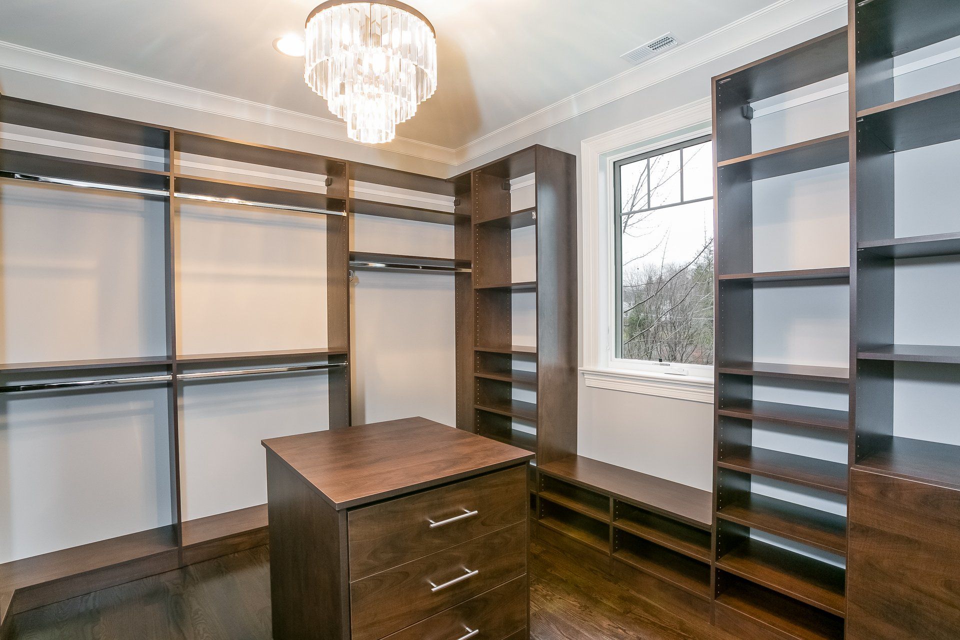 A walk in closet with lots of shelves and a chandelier hanging from the ceiling.