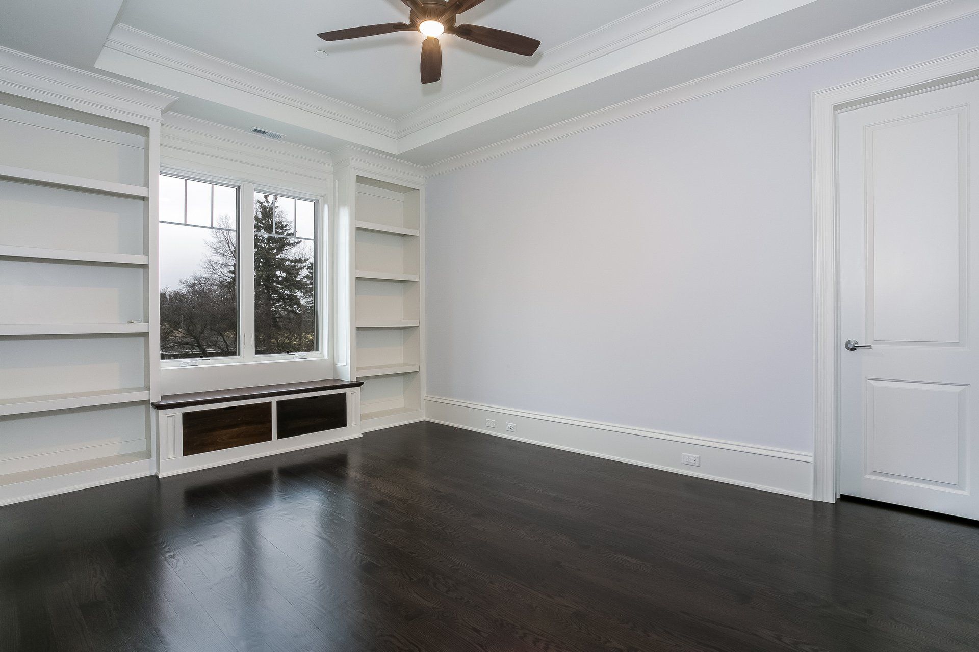 An empty room with a ceiling fan and shelves