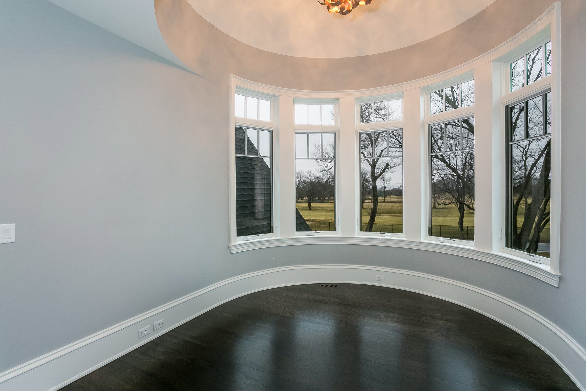 An empty room with a lot of windows and a chandelier