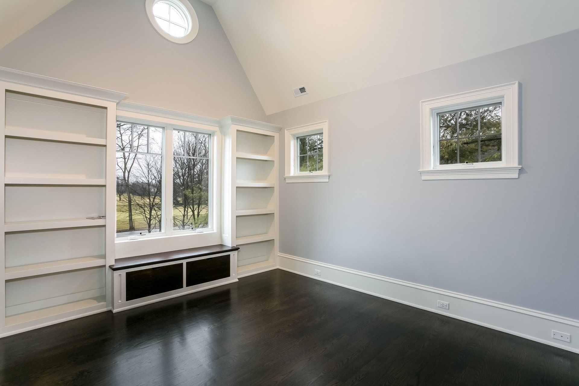 An empty room with a vaulted ceiling and lots of windows