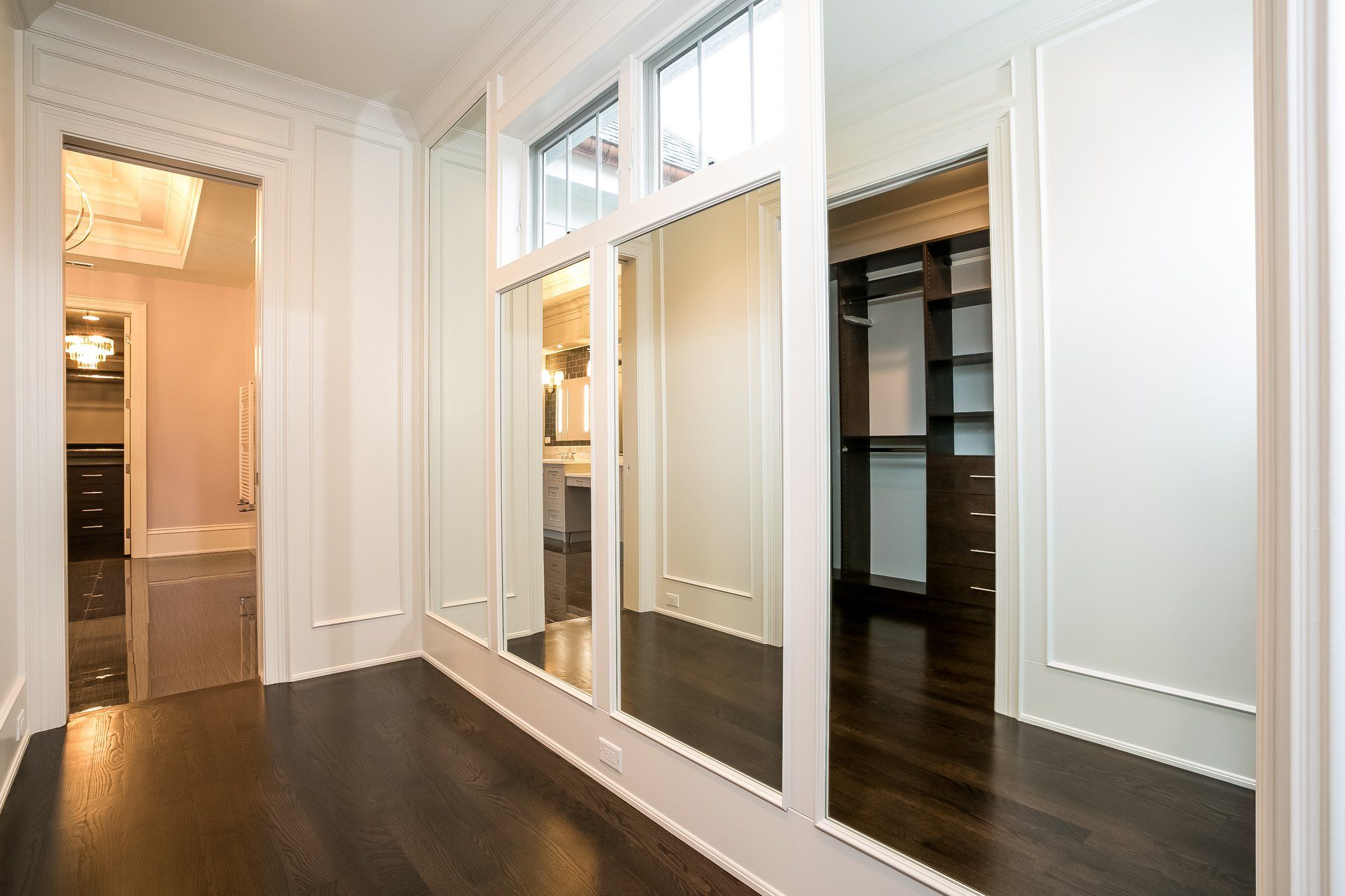 A walk in closet with a lot of mirrors on the wall.