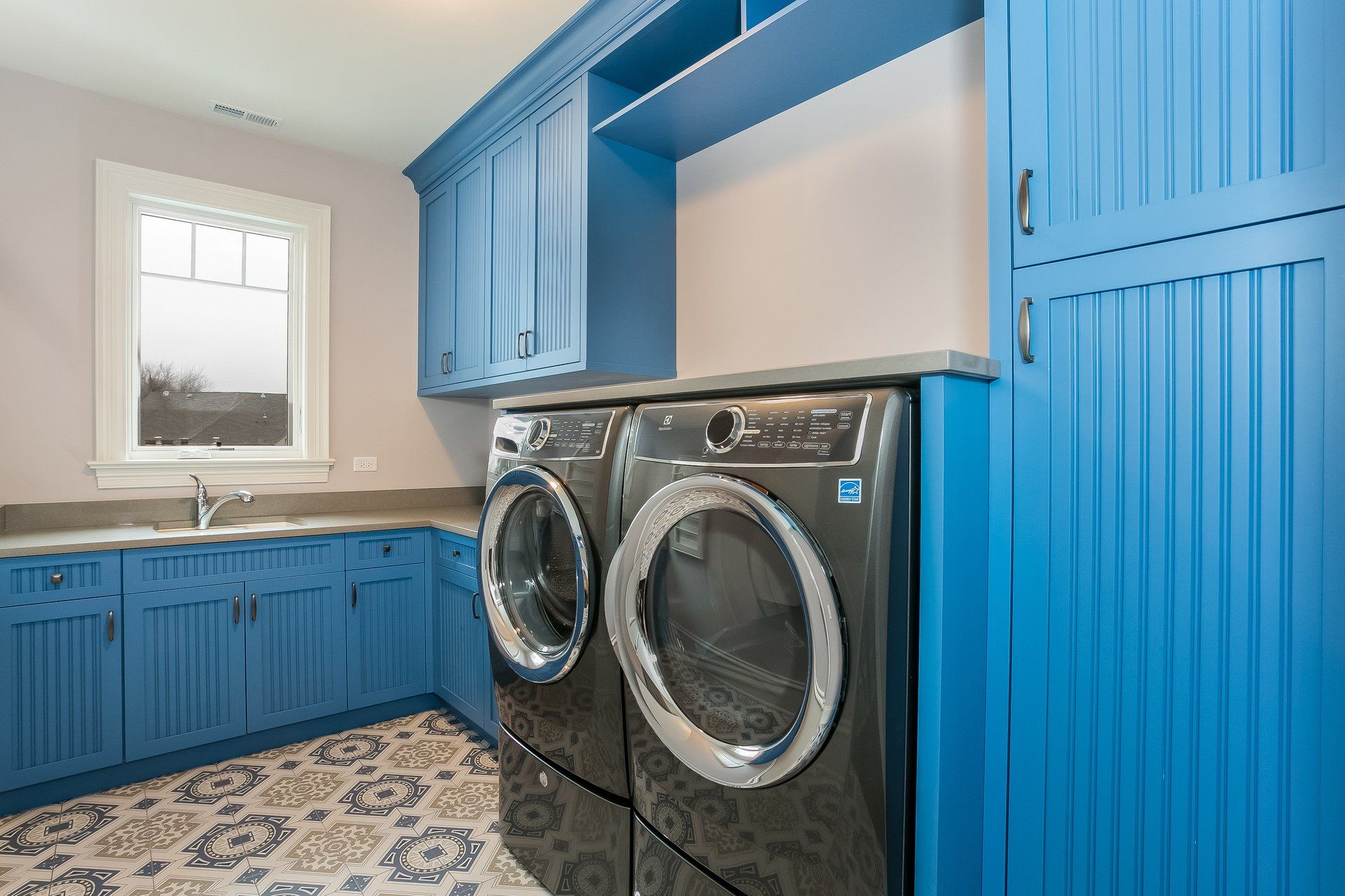 A laundry room with blue cabinets and a washer and dryer.