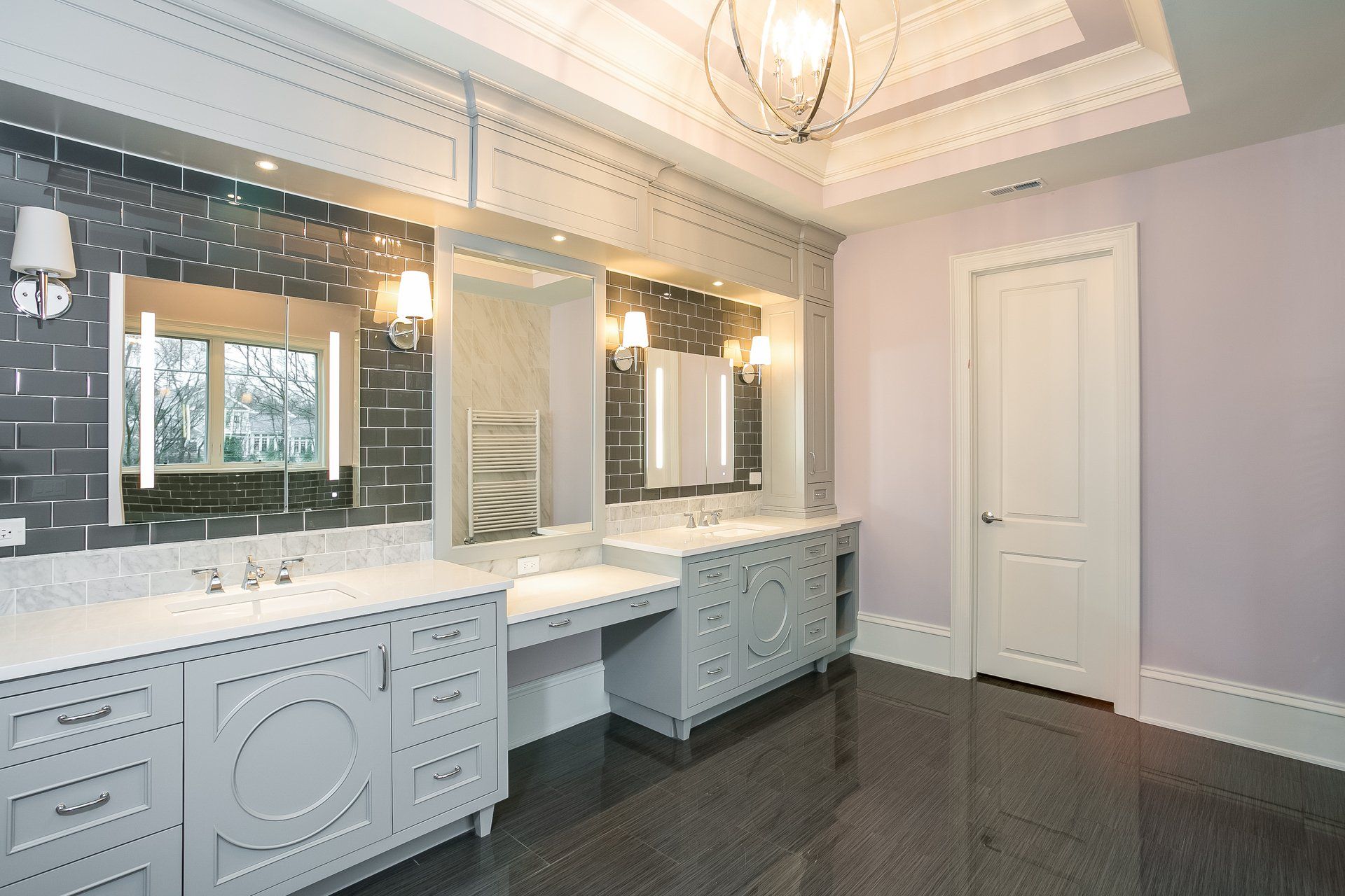 A bathroom with two sinks , two mirrors and a chandelier.