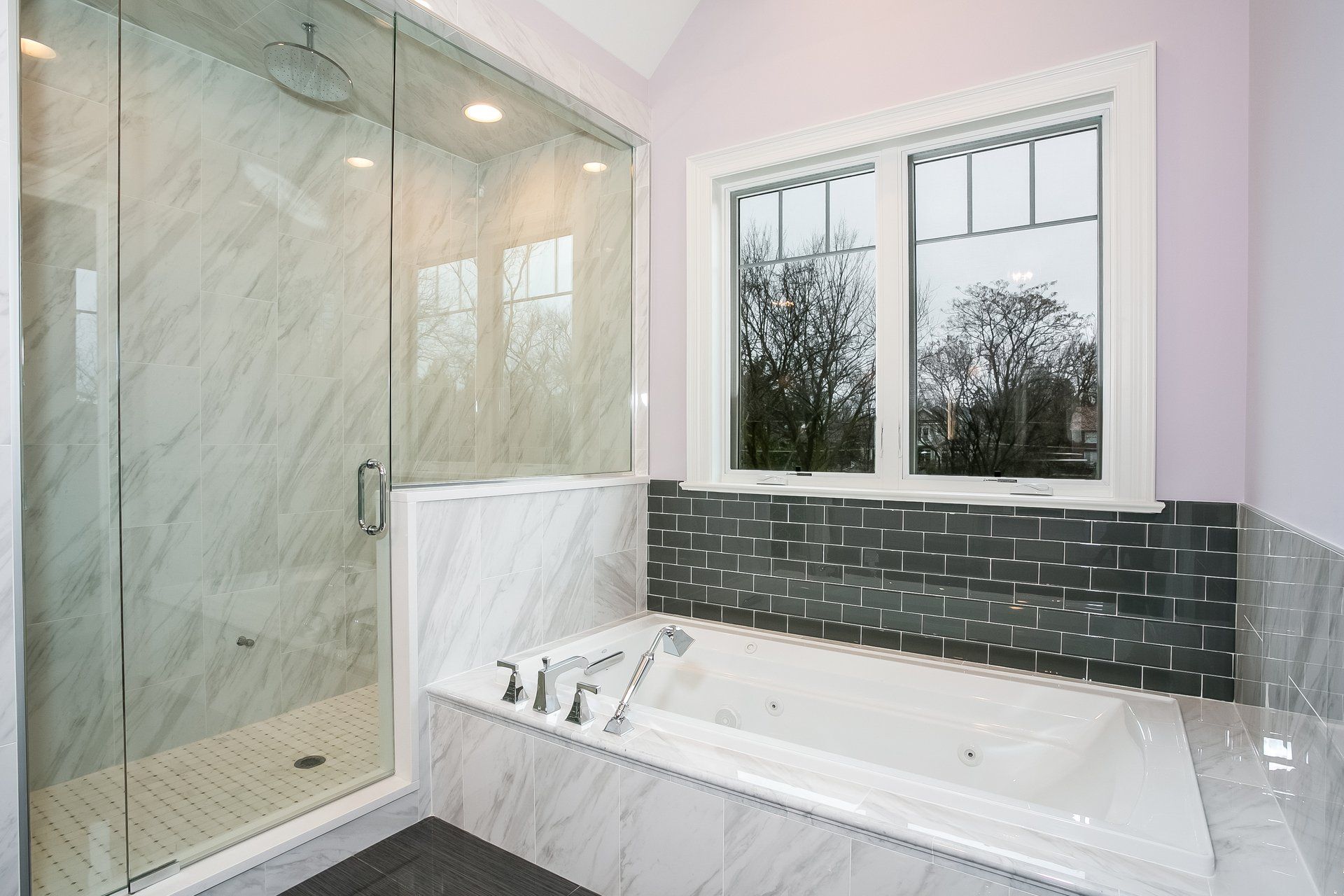 A bathroom with a tub , shower , and window.