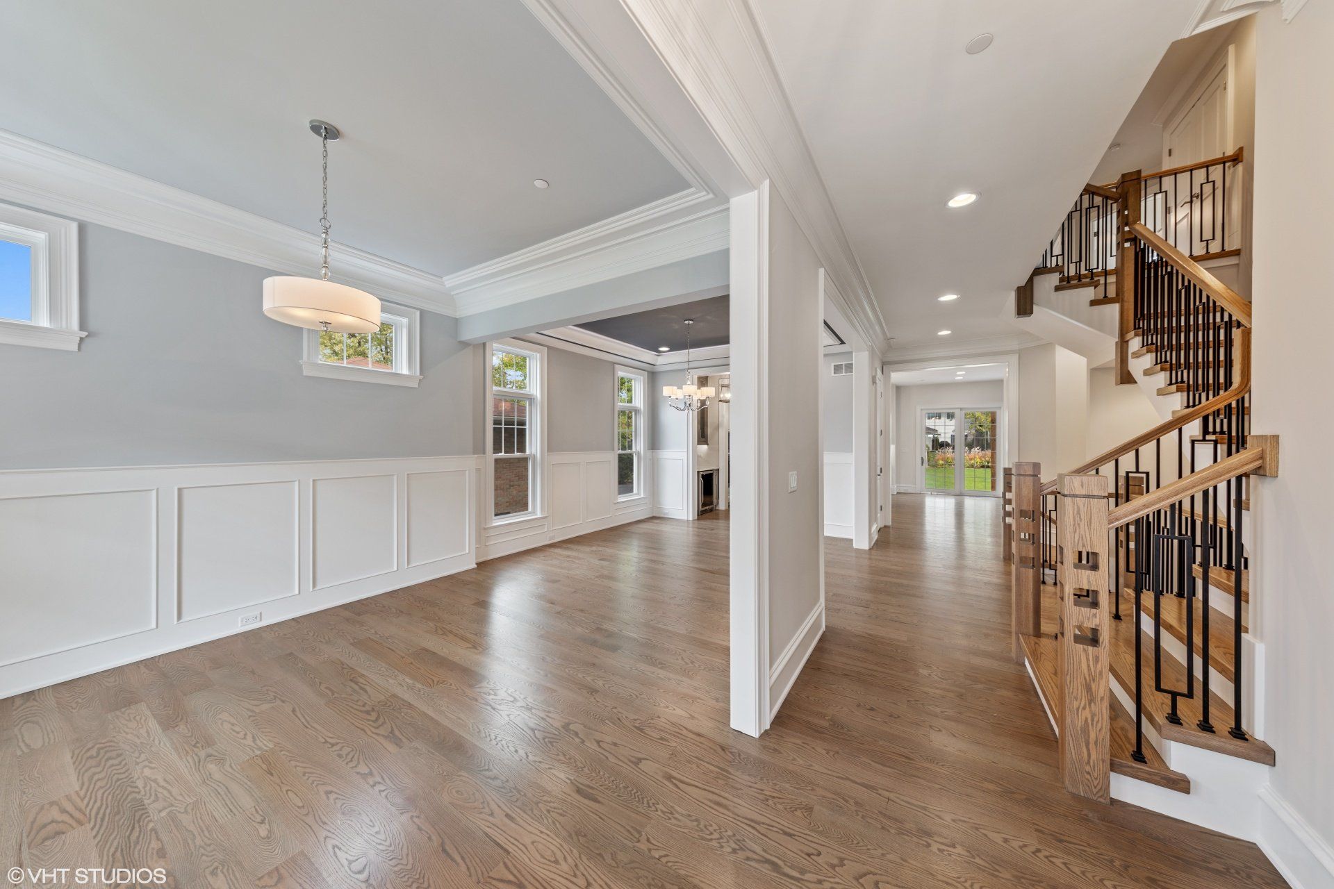 A large empty room with hardwood floors and stairs in a house.