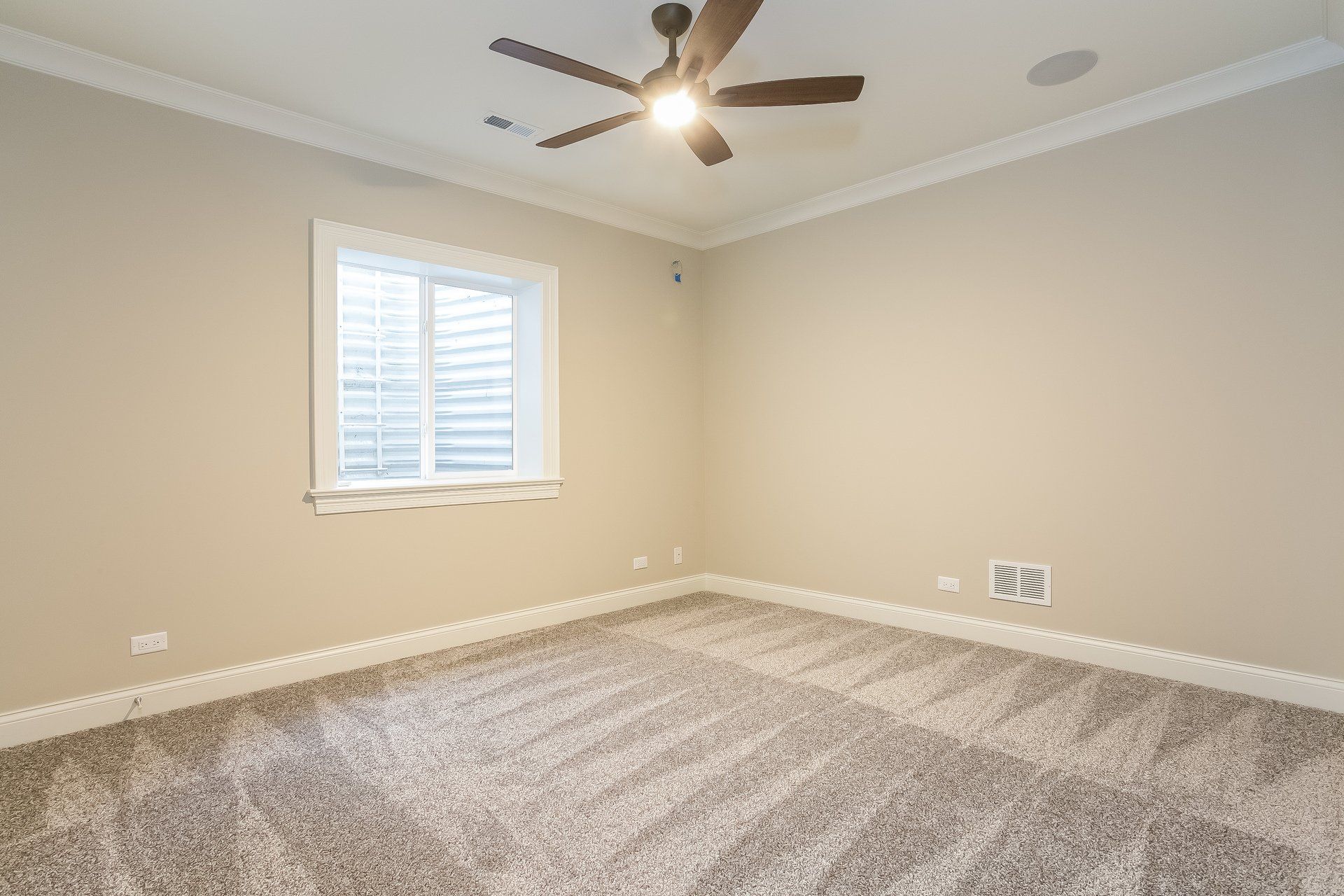 An empty bedroom with a ceiling fan and a window.