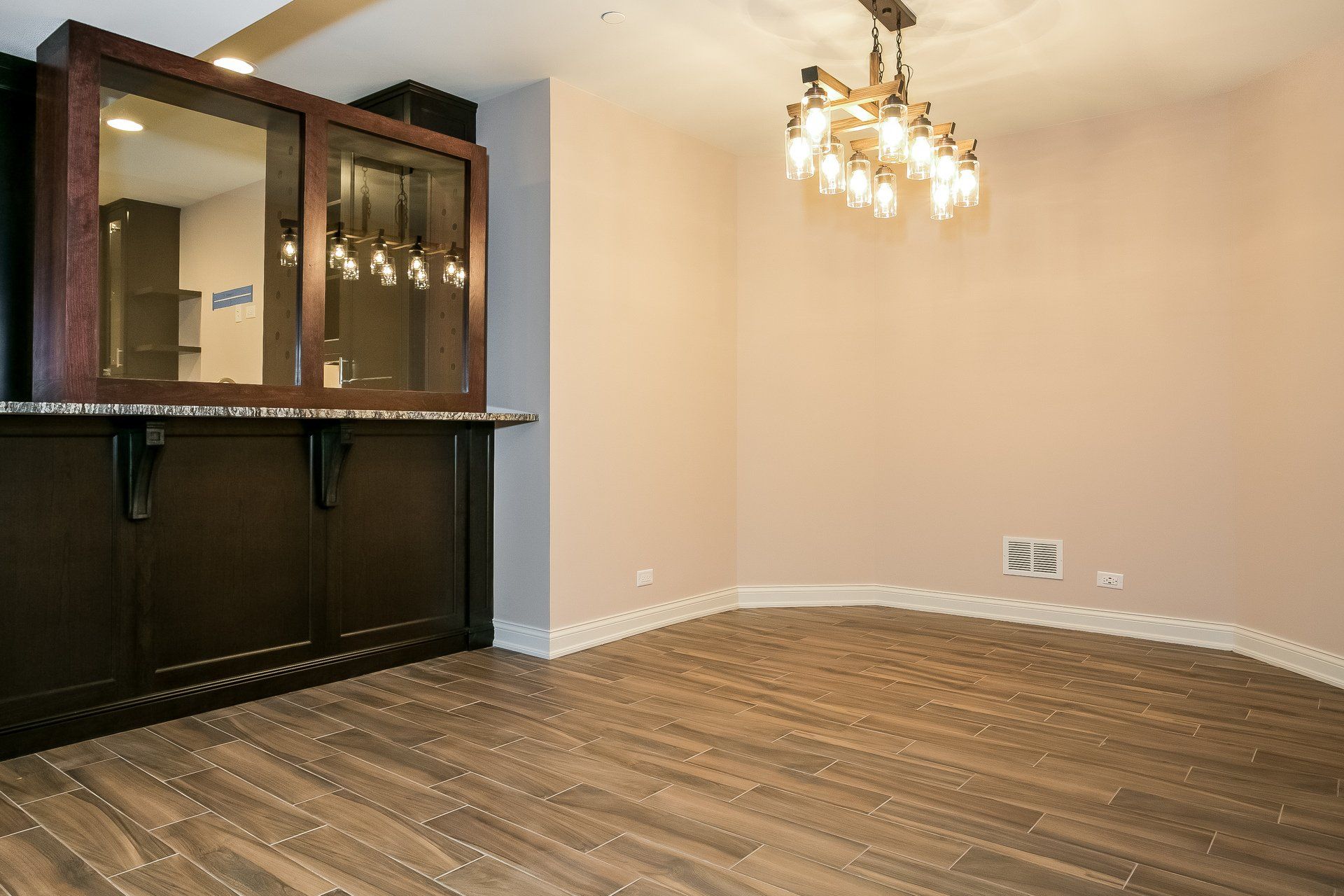 An empty living room with hardwood floors and a chandelier.