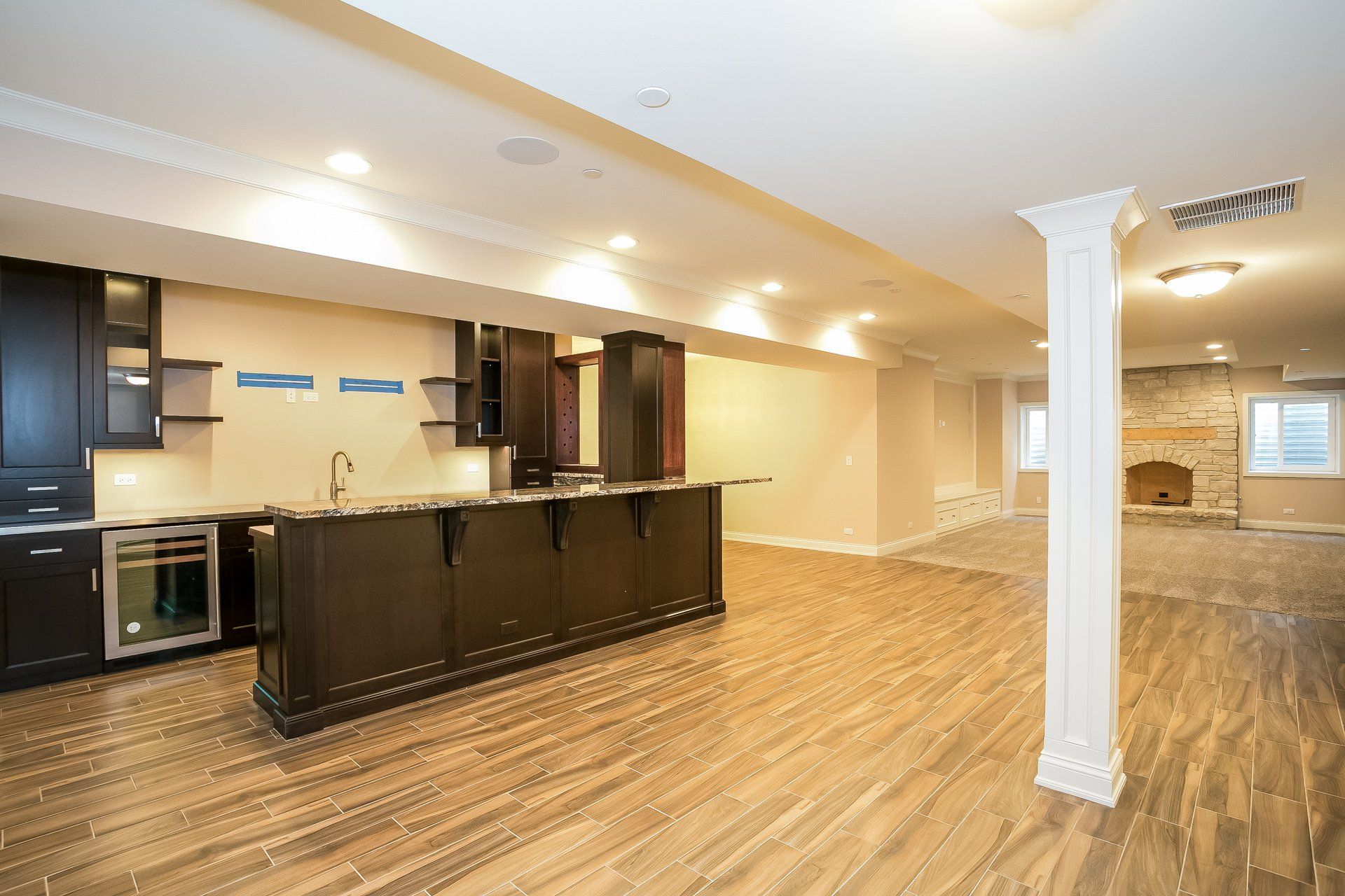 An empty basement with a kitchen and a bar.