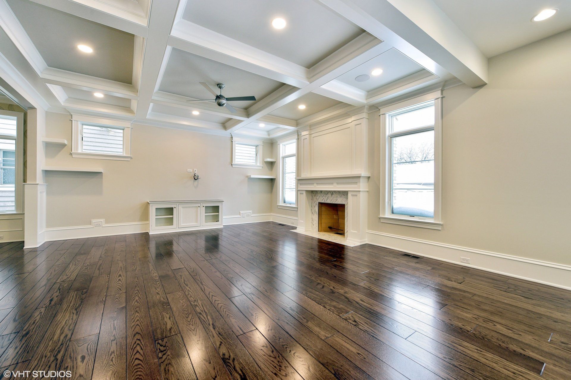 An empty living room with hardwood floors and a fireplace.