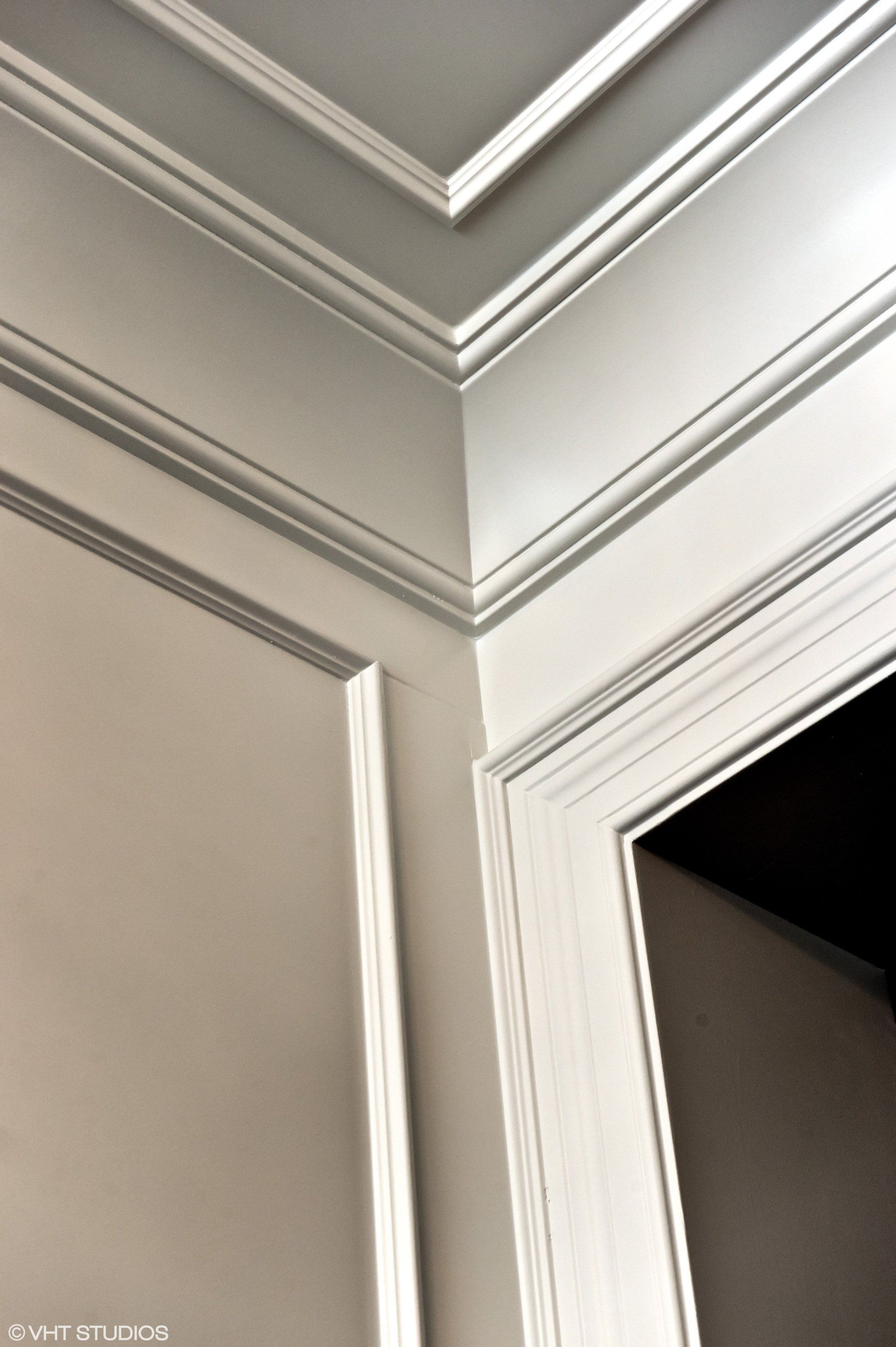 A corner of a room with a crown molding on the ceiling