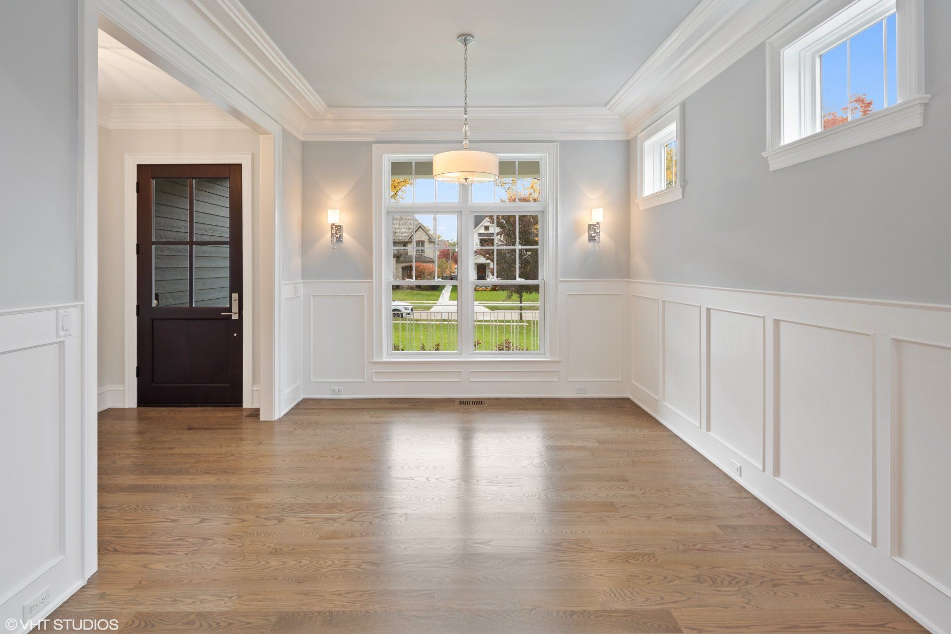 An empty dining room with hardwood floors and white trim.