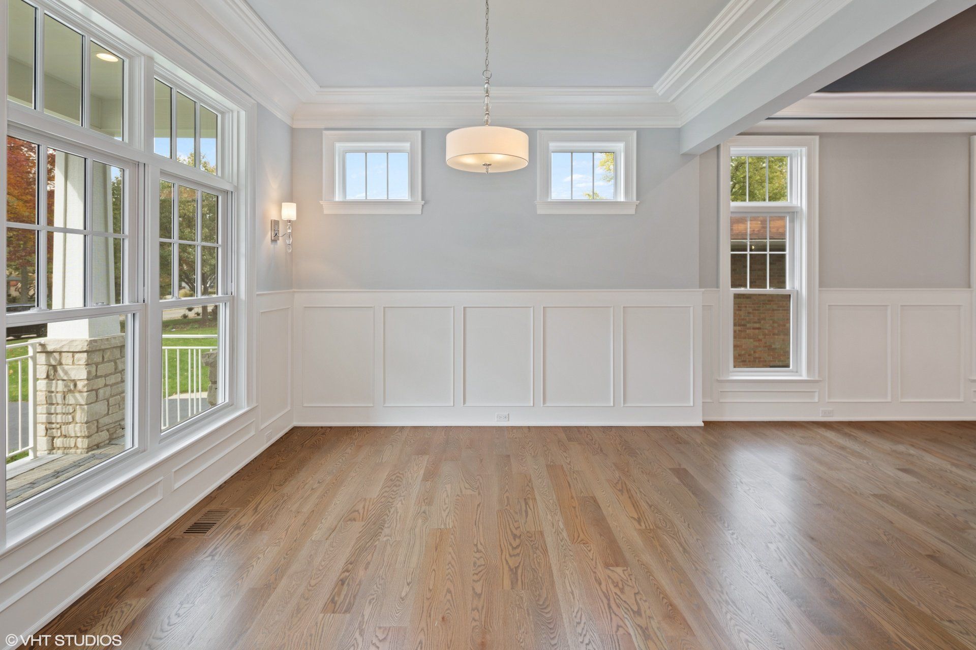 An empty room with hardwood floors and lots of windows.