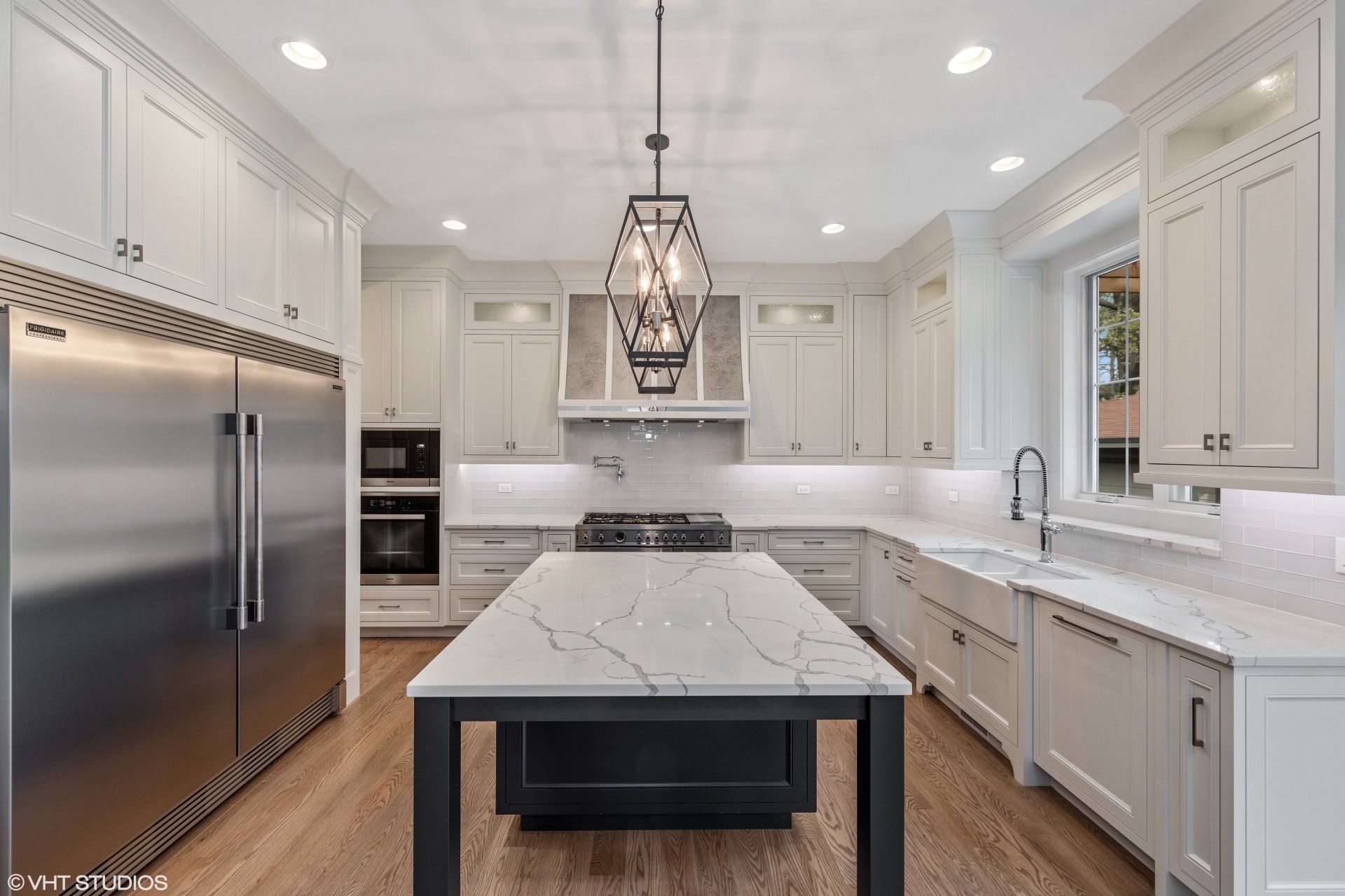 A kitchen with white cabinets , stainless steel appliances , and a large island.