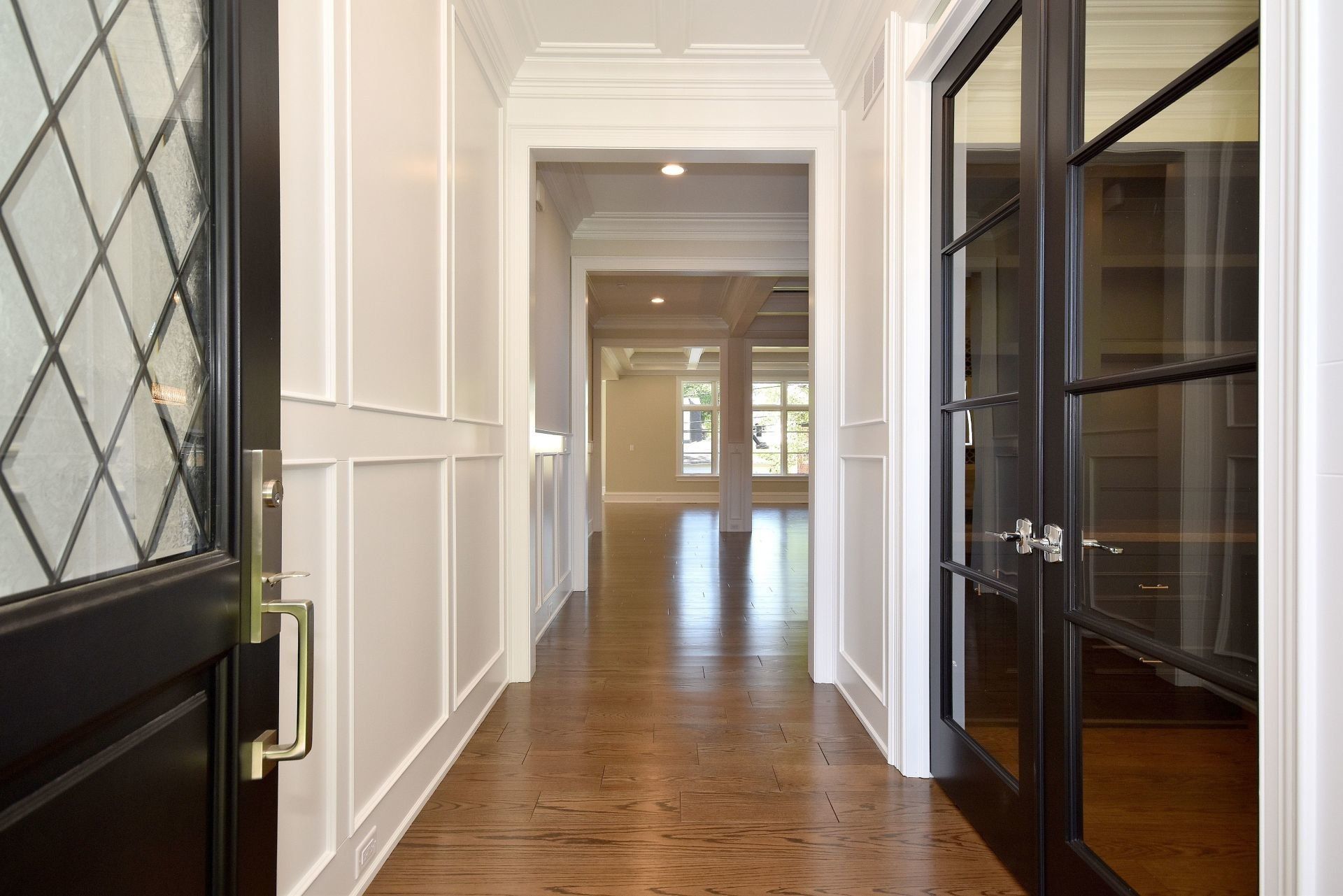 A hallway in a house with hardwood floors and black doors.