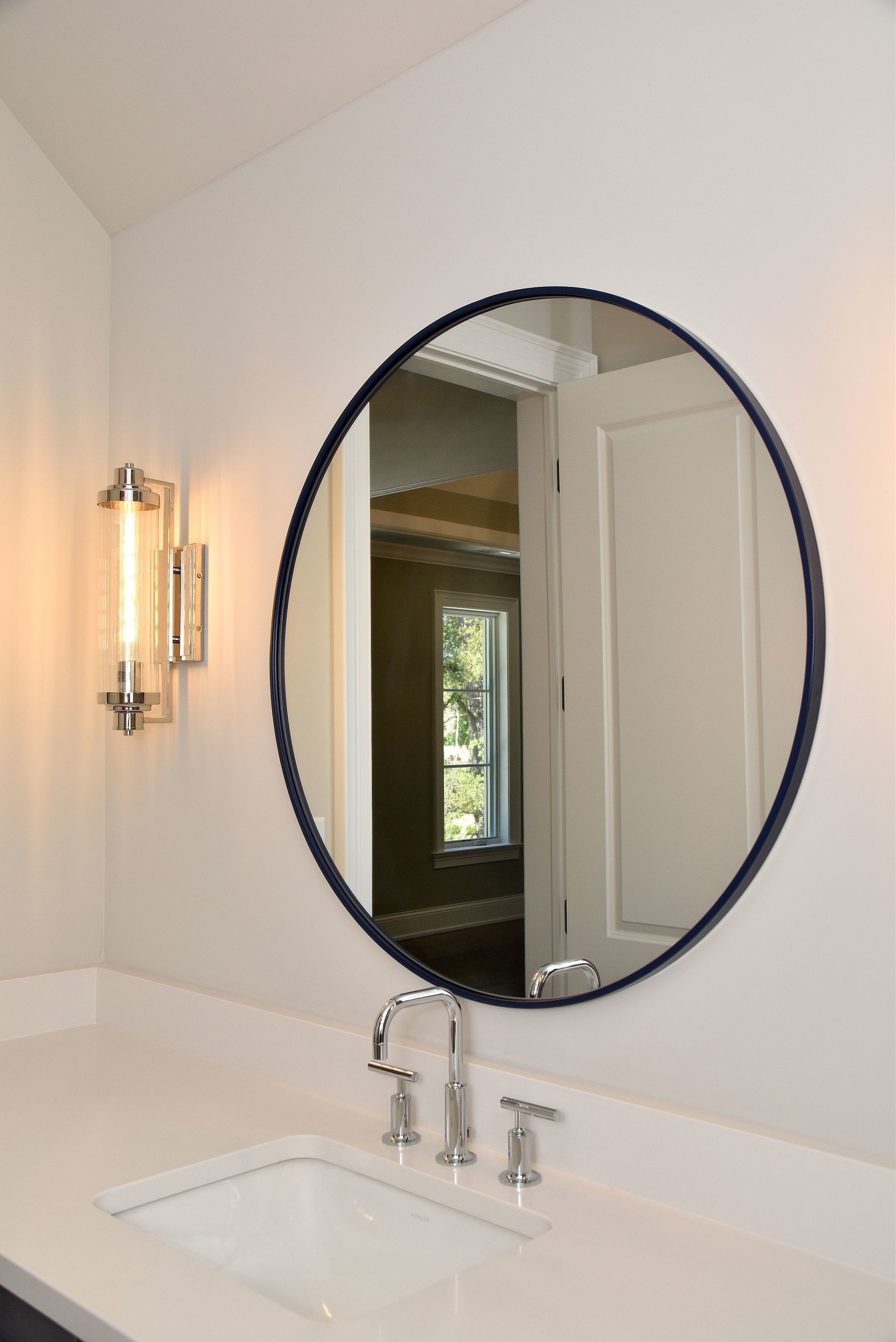 A bathroom with a round mirror and a sink.