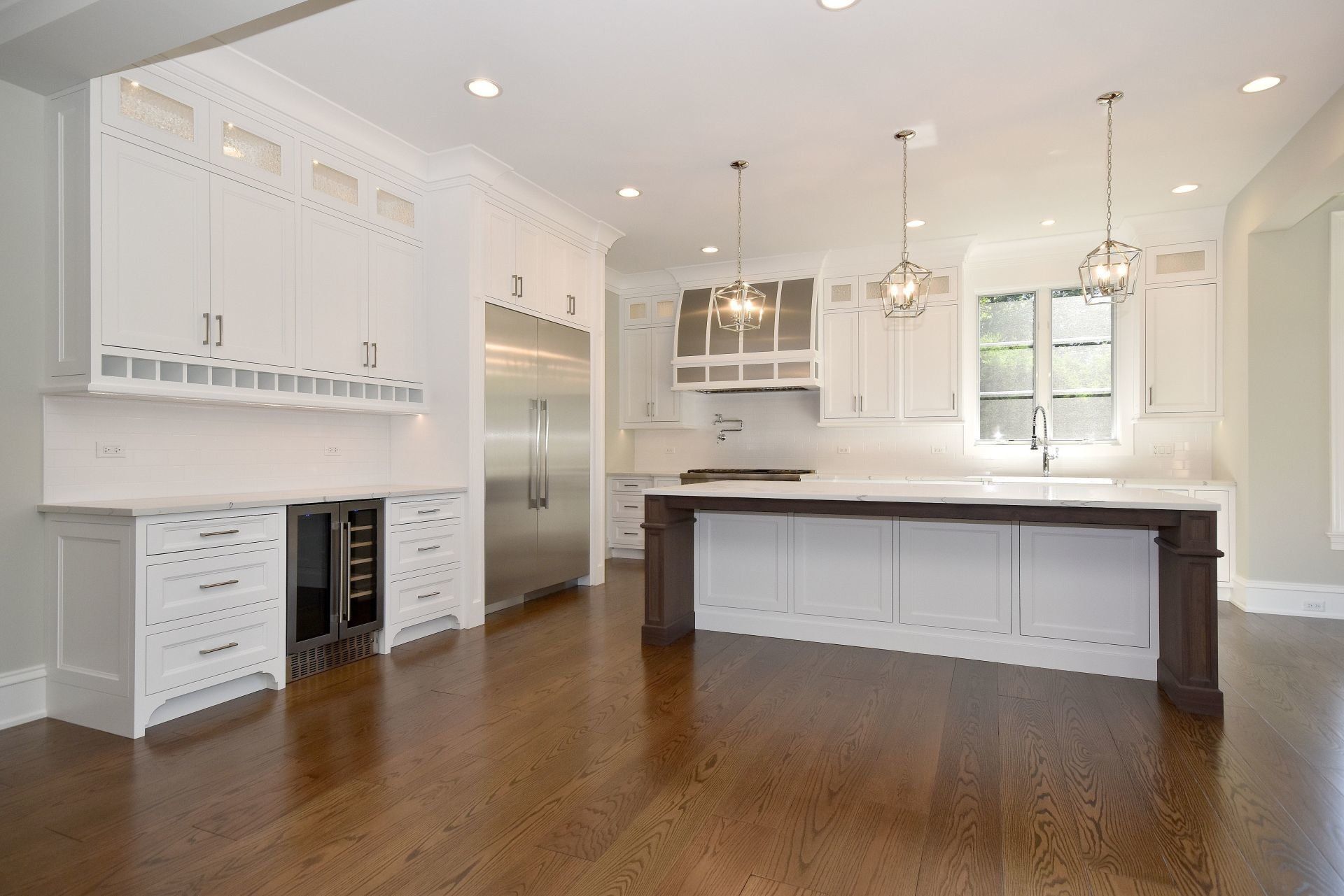 An empty kitchen with white cabinets and stainless steel appliances