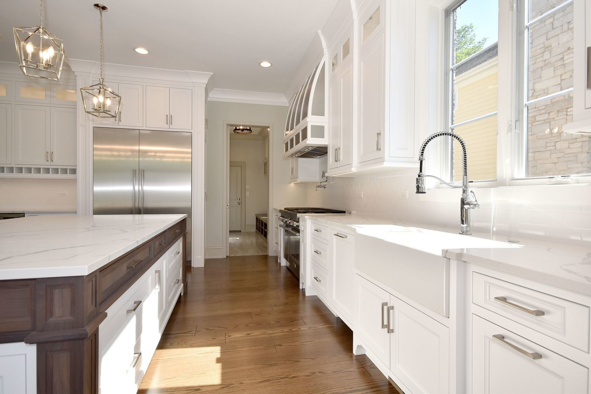 A kitchen with white cabinets , stainless steel appliances , a sink , and a large island.