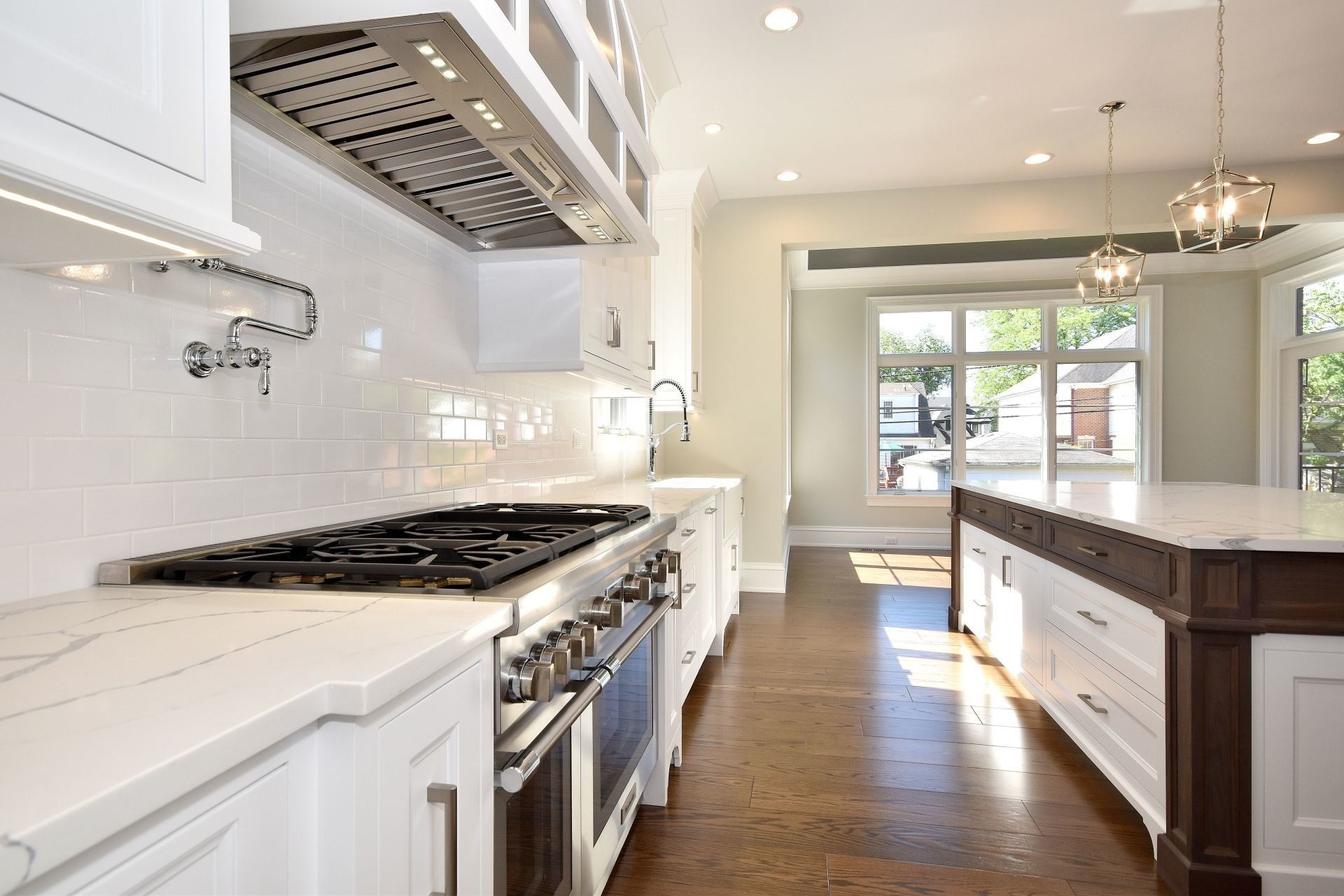 A kitchen with white cabinets , stainless steel appliances and a large island.