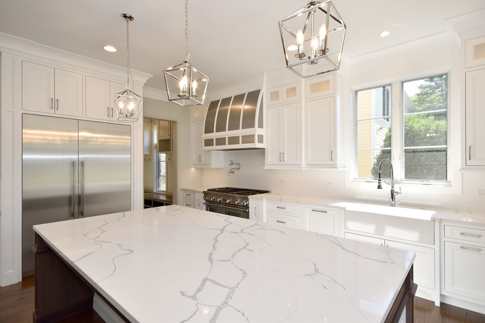 A kitchen with white cabinets , stainless steel appliances , and a large island.