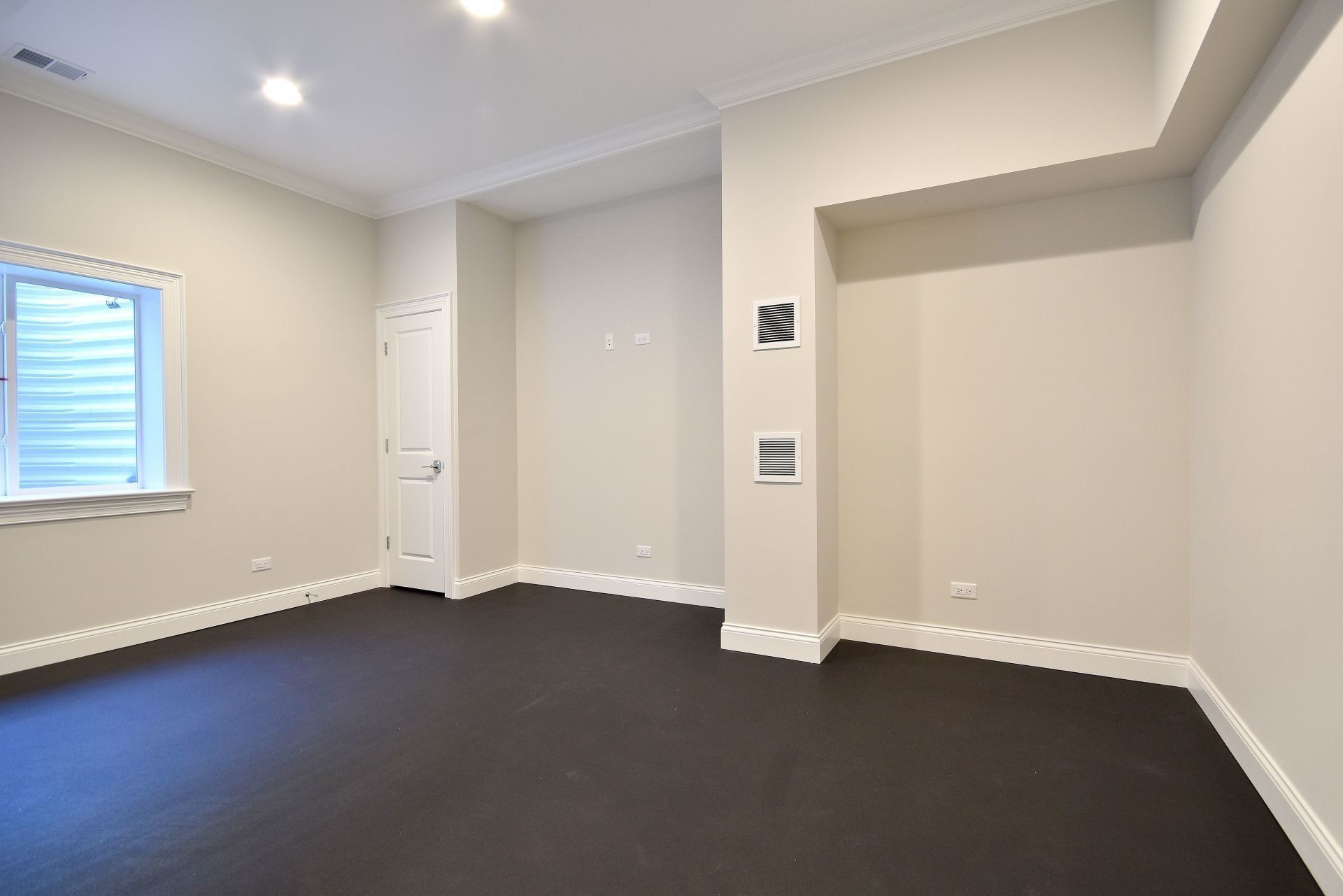 An empty room with a window and black carpet