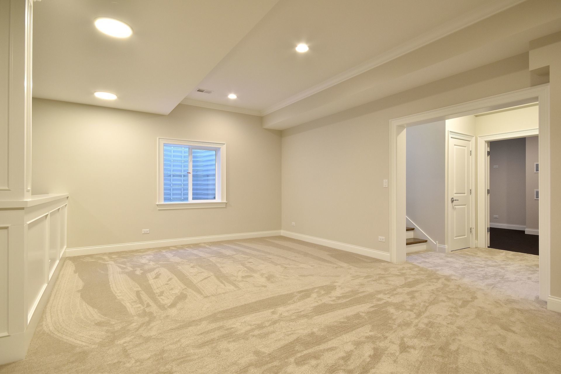 An empty basement with a carpeted floor and a window.