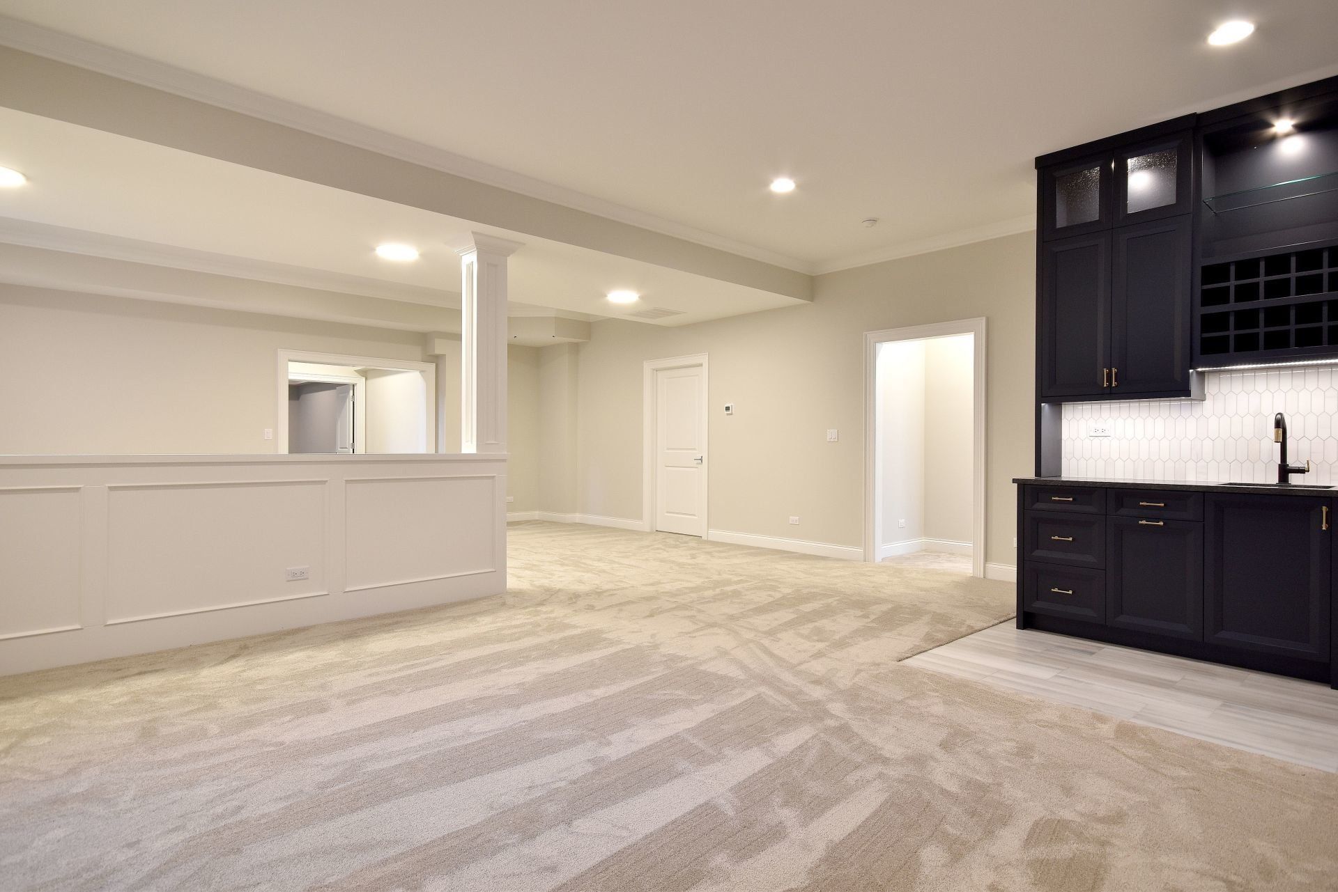 An empty basement with a bar and cabinets.