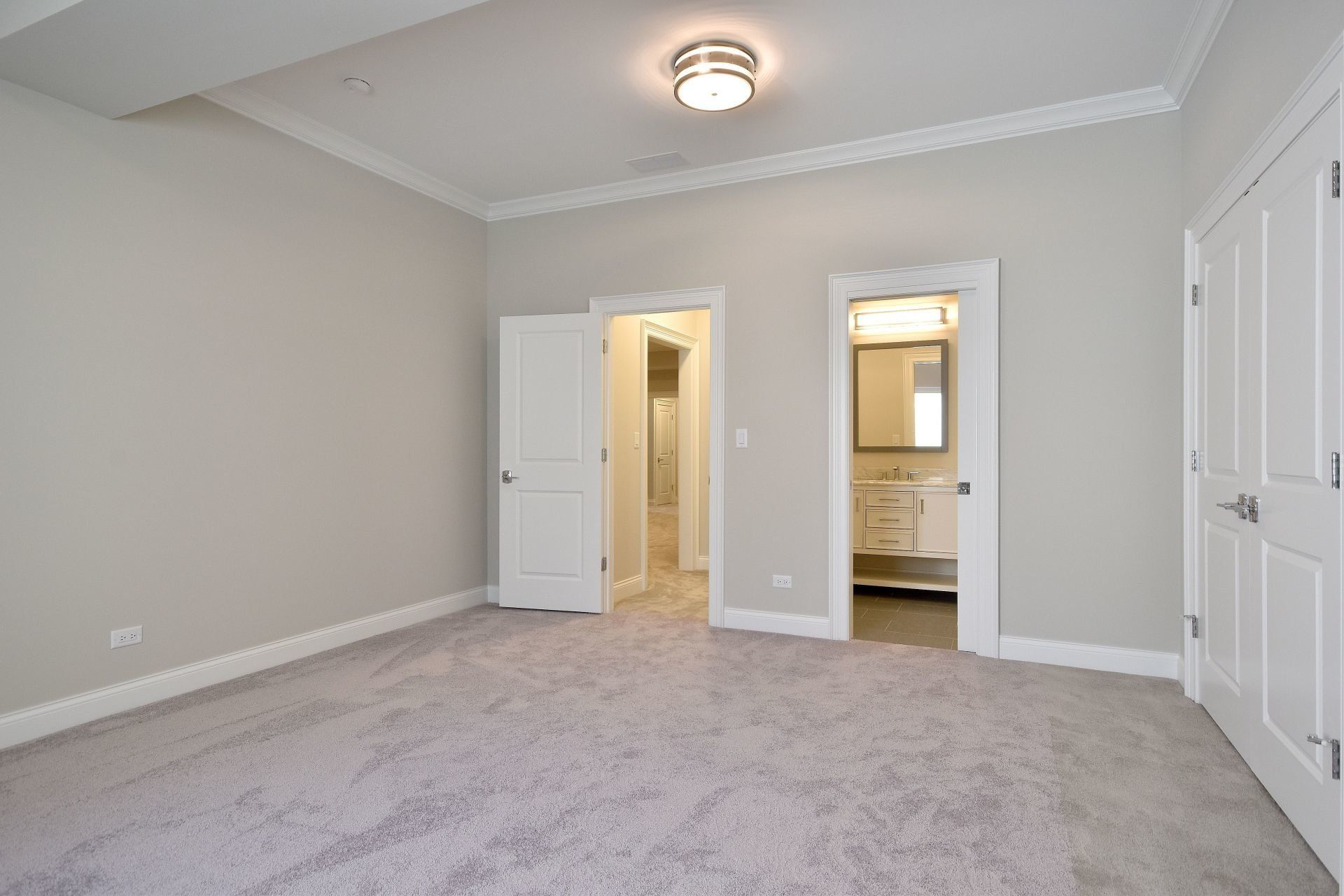An empty bedroom with a carpeted floor and a bathroom