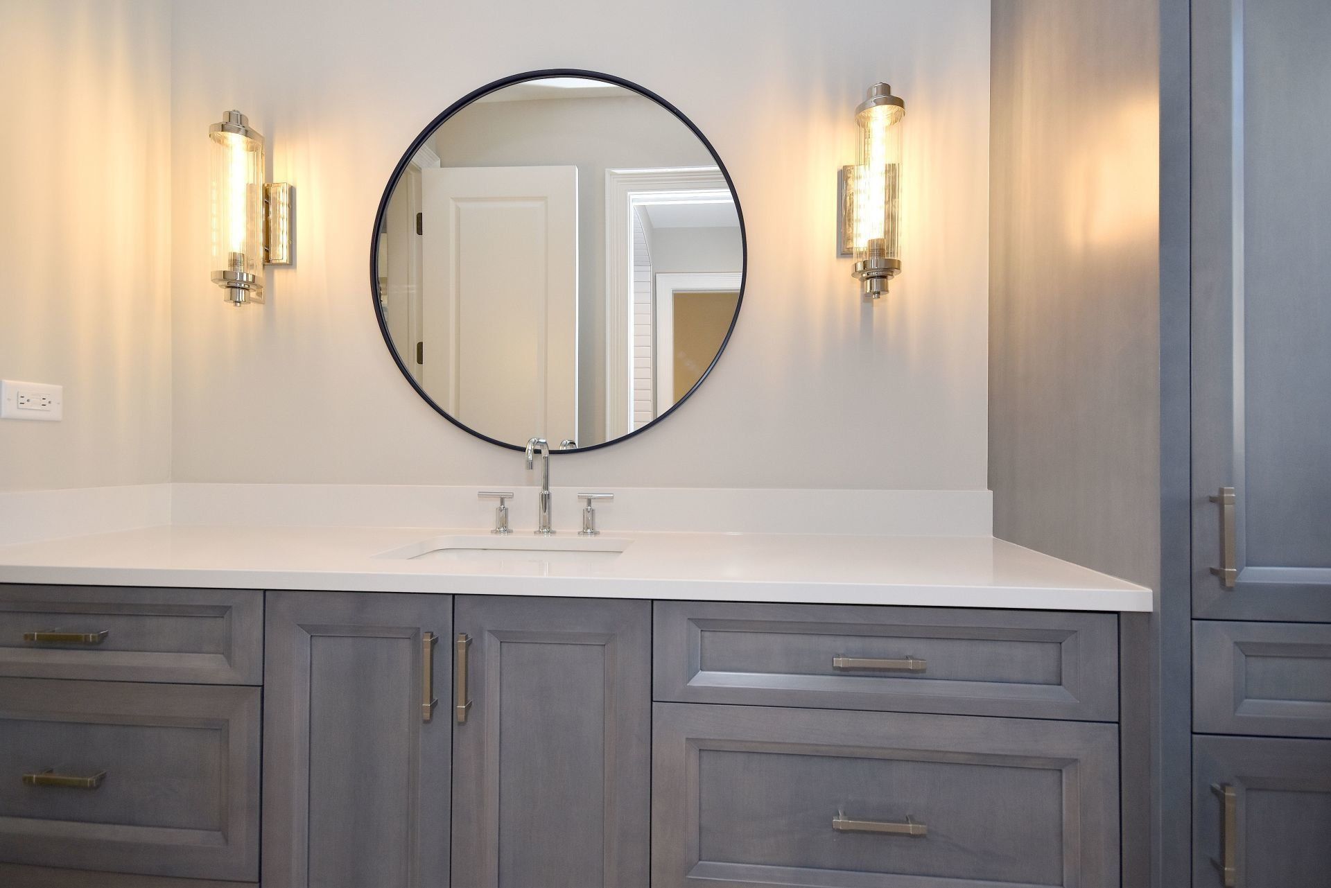 A bathroom with a sink and a round mirror.