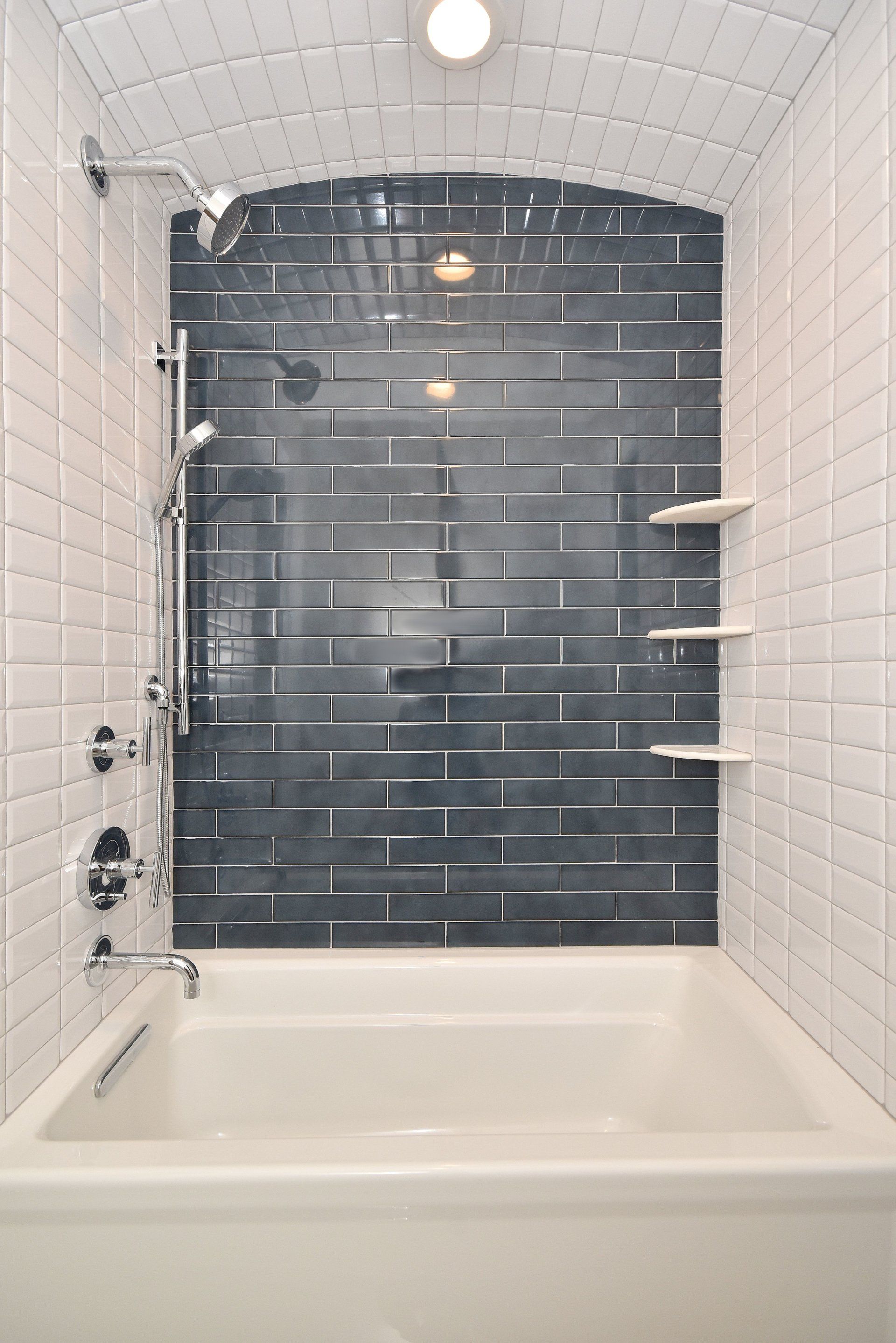A bathroom with a bathtub , shower , and brick wall.