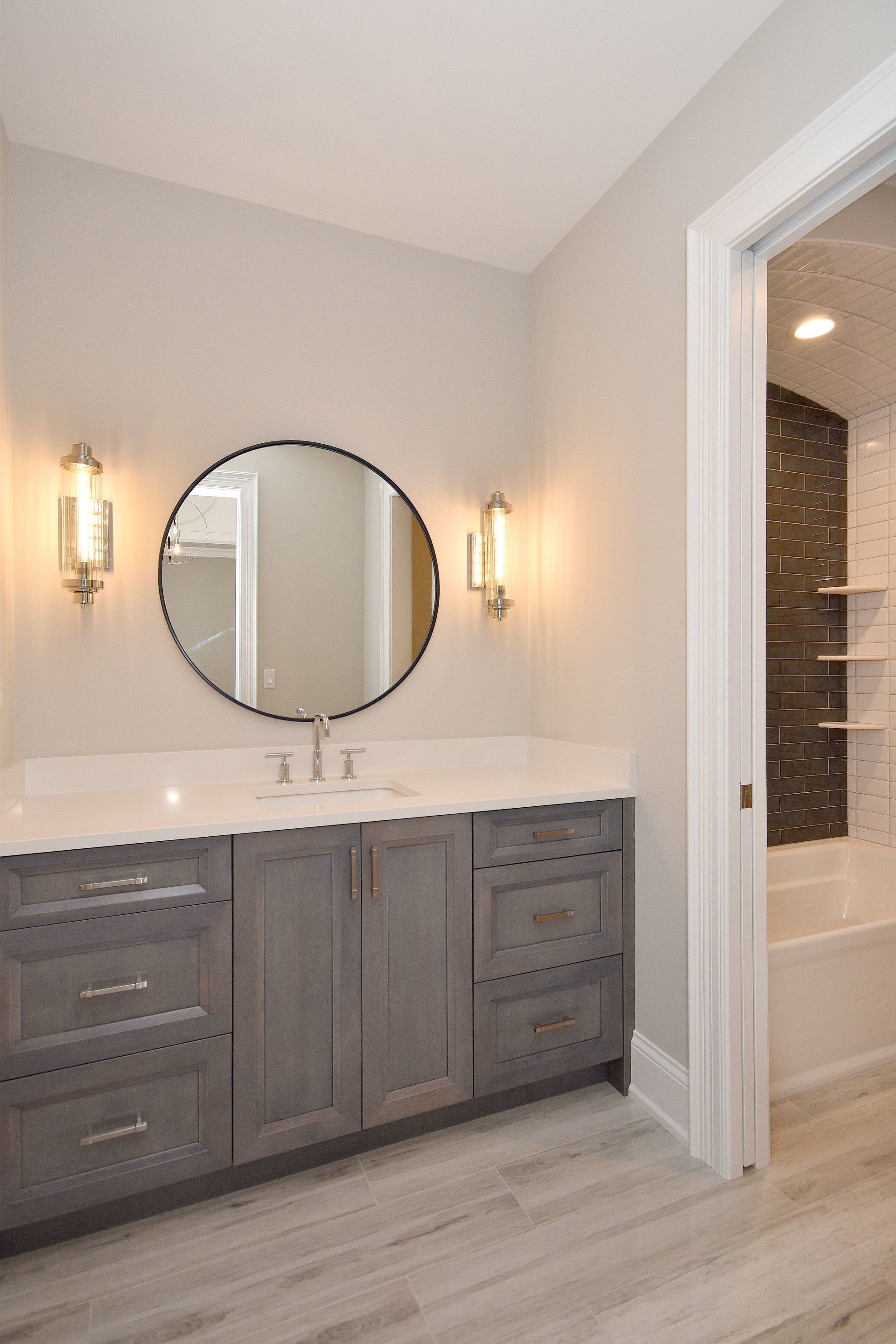 A bathroom with a sink and a round mirror.