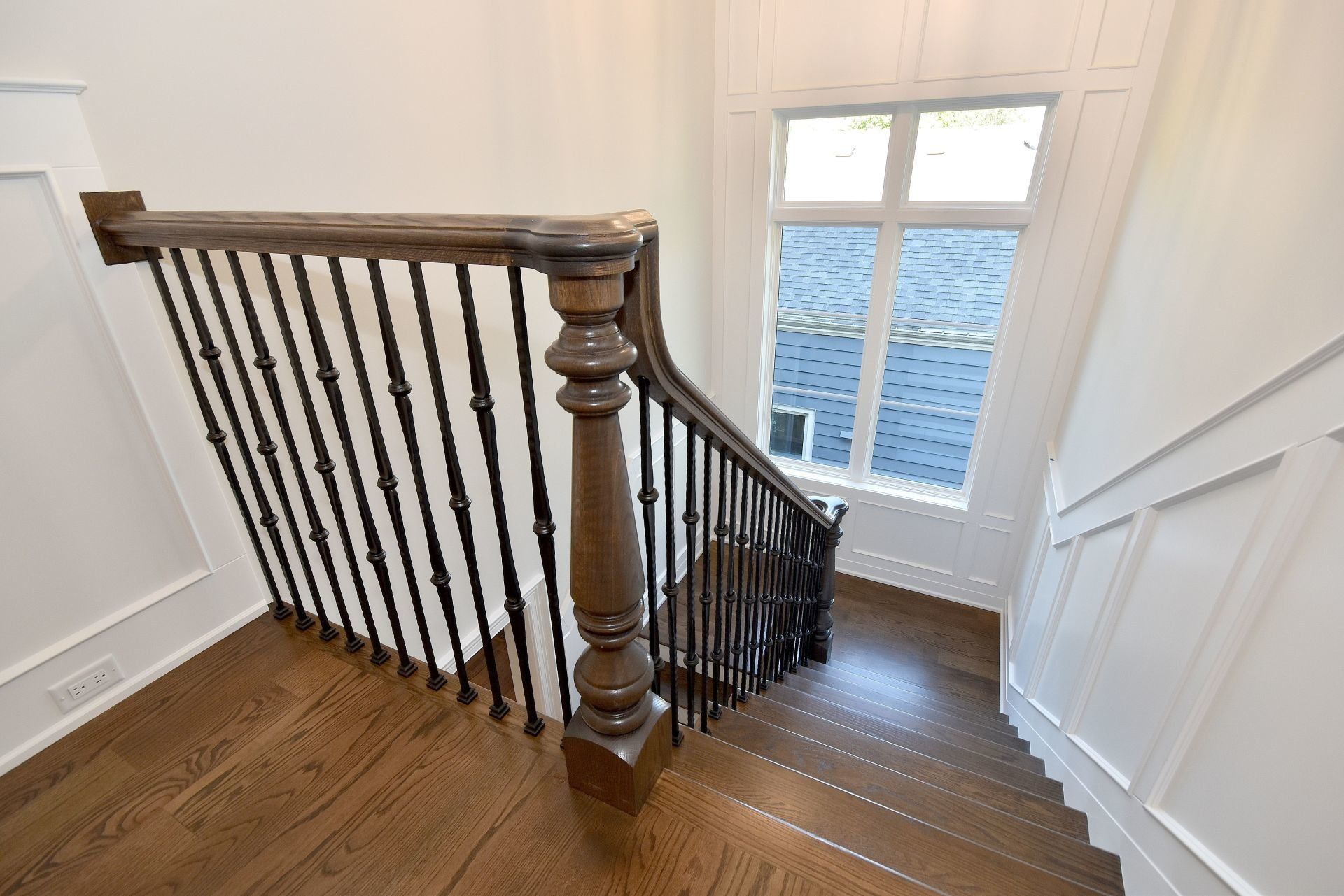 A wooden staircase with a wrought iron railing and a window.