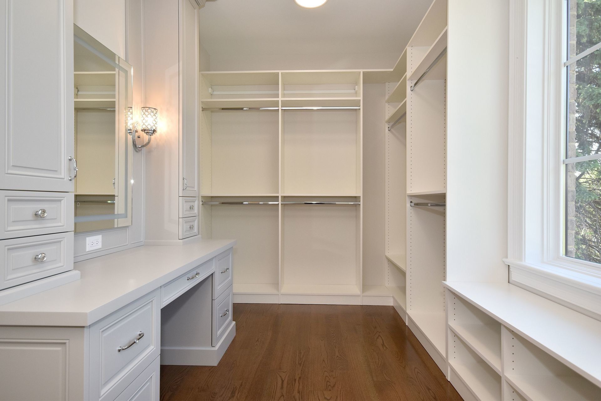 A walk in closet with lots of shelves and drawers and a vanity.