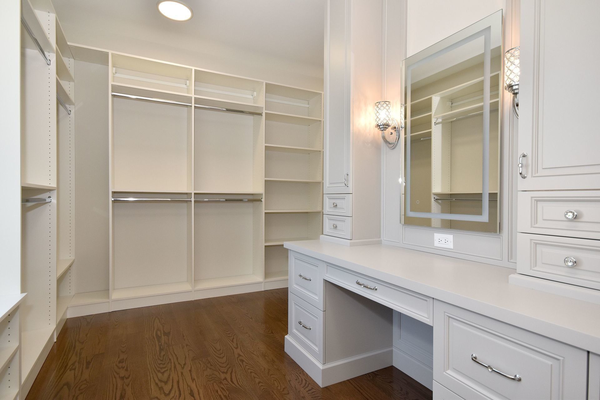 A walk in closet with a desk and a mirror.