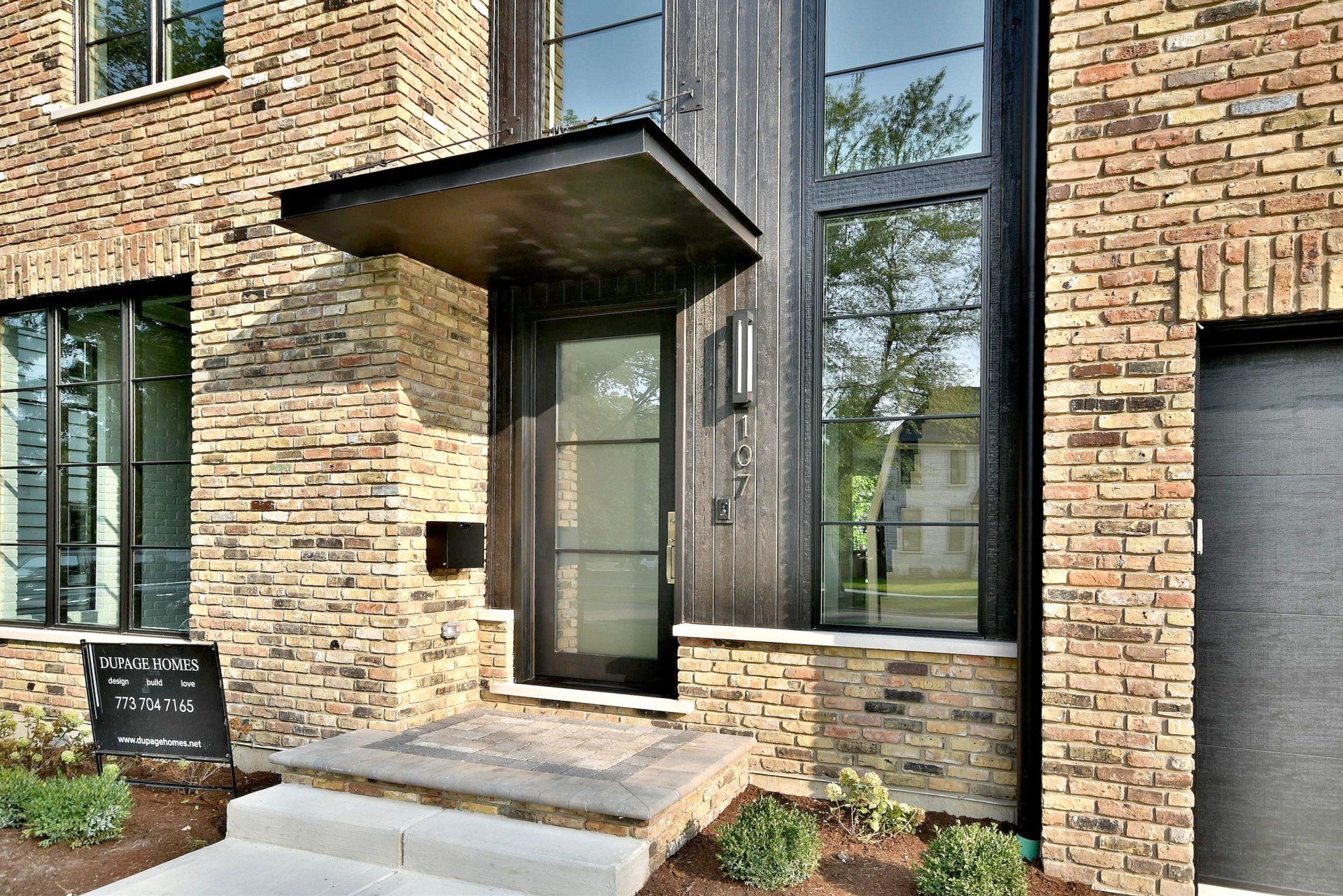 The front door of a brick house with a canopy over it.