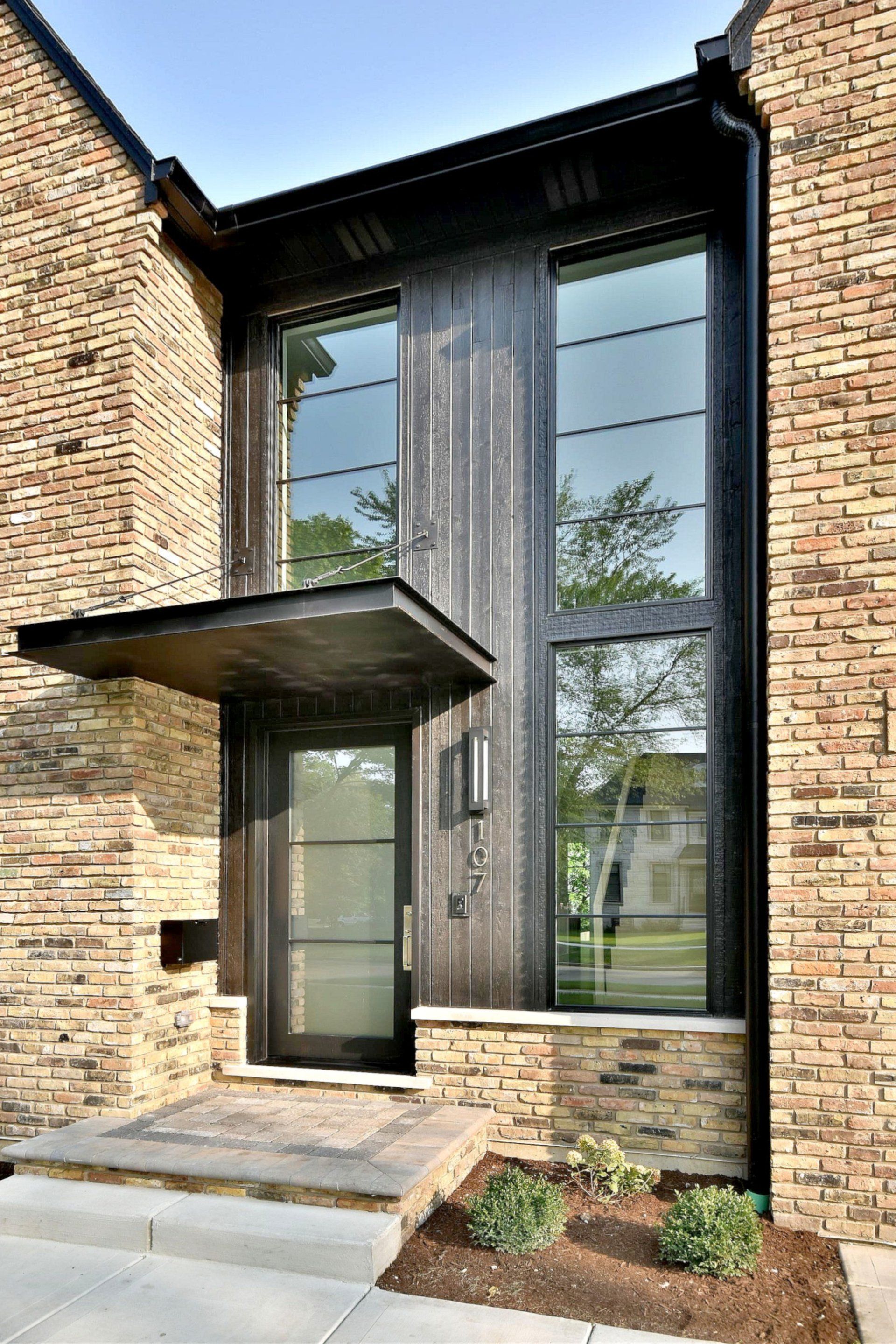 The front door of a brick house with a canopy over it.