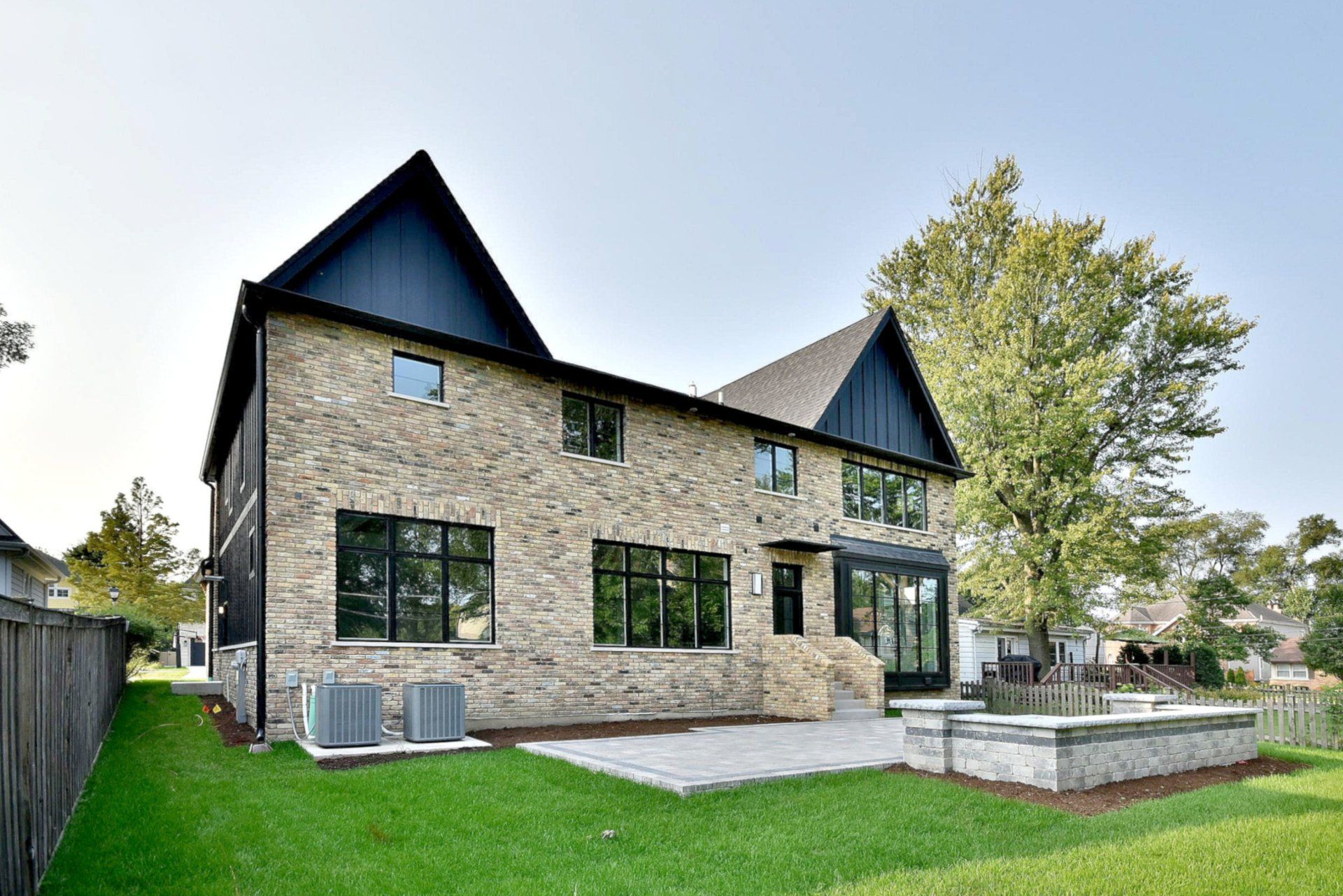 The back of a large brick house with a large lawn in front of it.