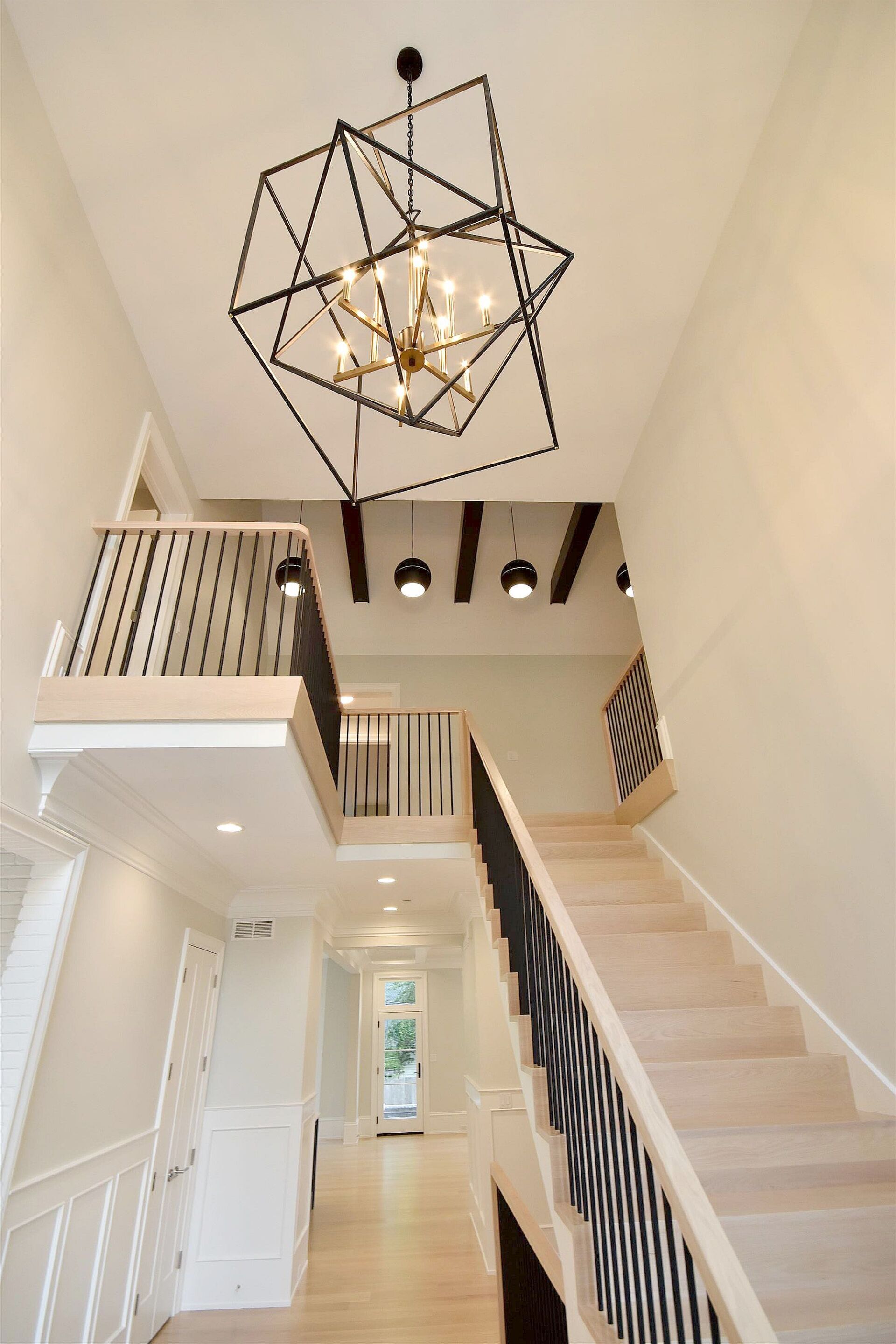 A hallway with stairs and a chandelier hanging from the ceiling.