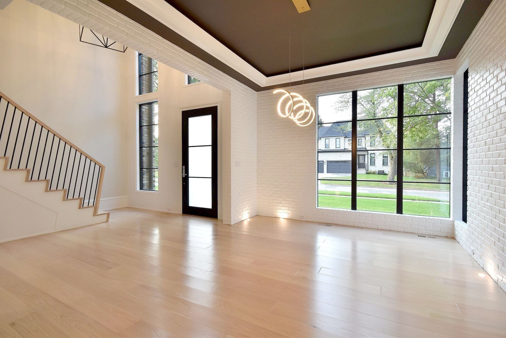 An empty living room with hardwood floors and a staircase.
