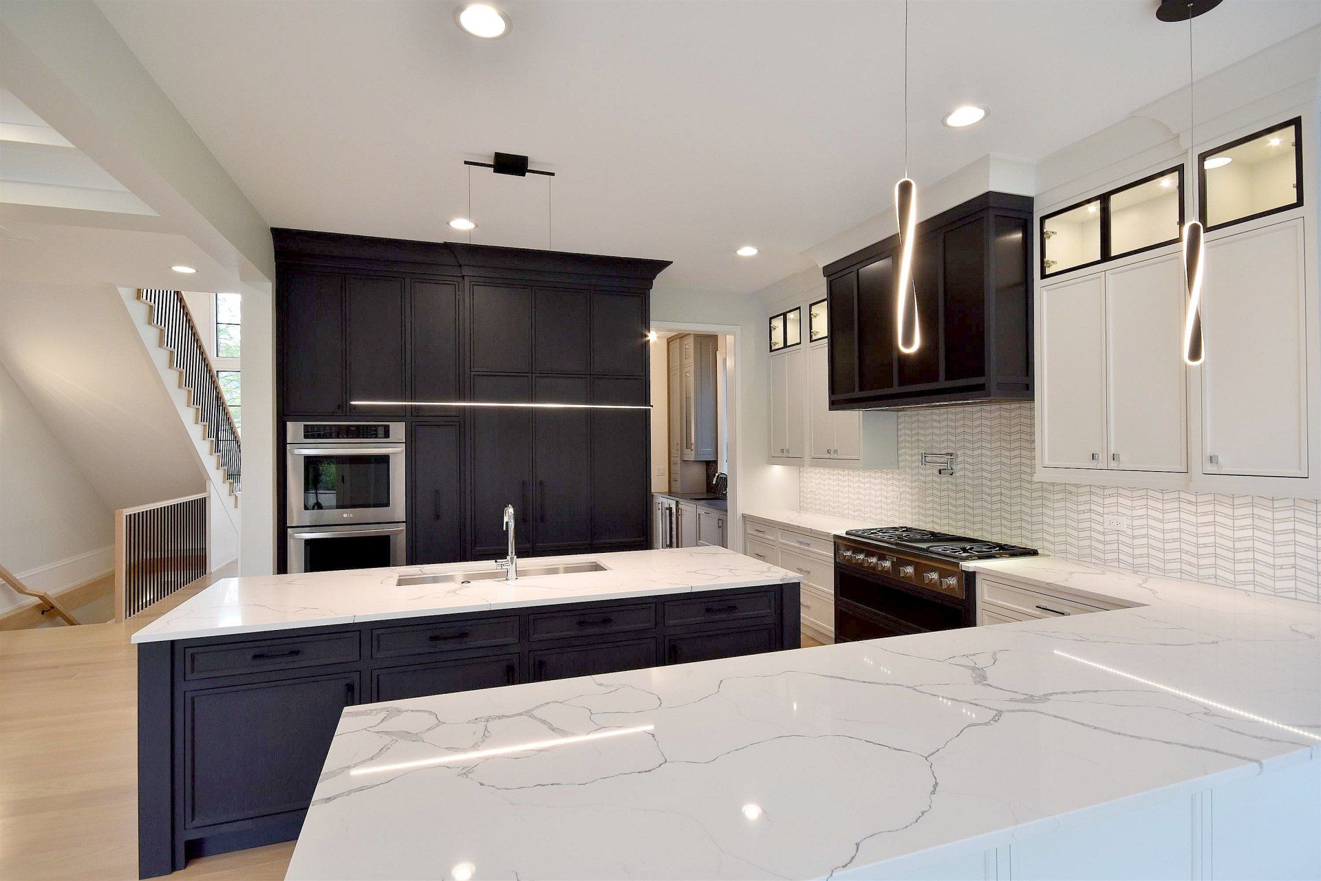 A kitchen with black cabinets and white counter tops and a large island.