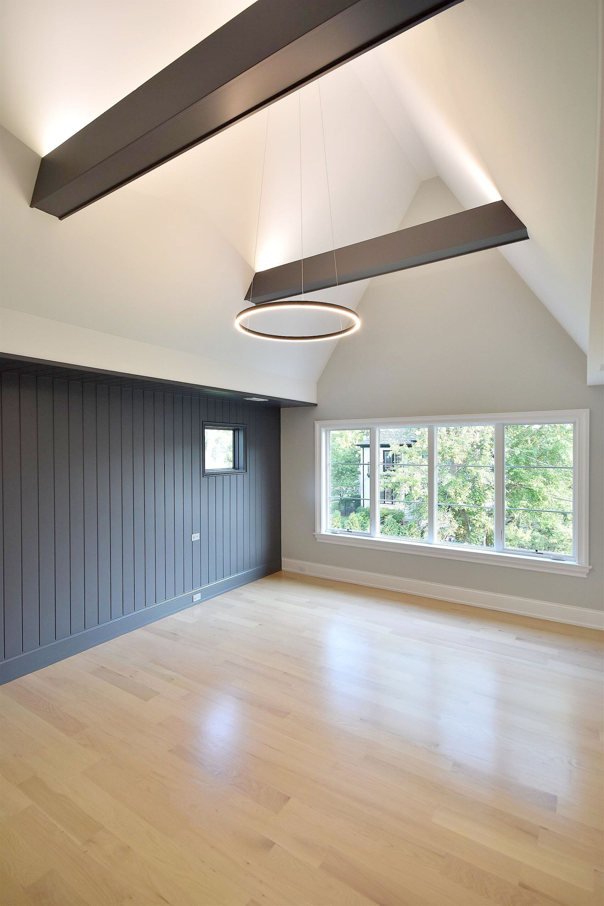 A large empty room with a lot of windows and a chandelier hanging from the ceiling.